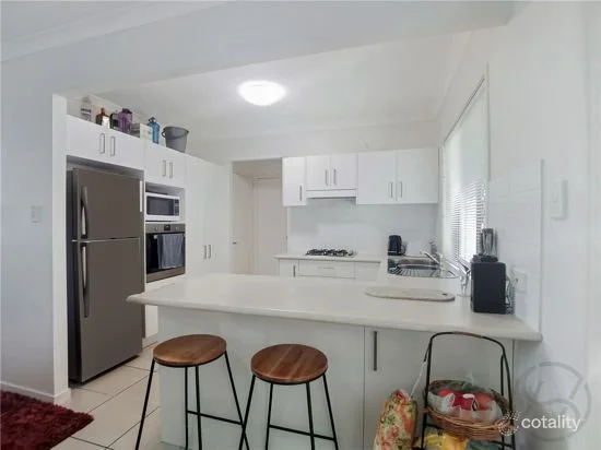 Original kitchen with white cabinetry, laminate benchtop and breakfast bar seating