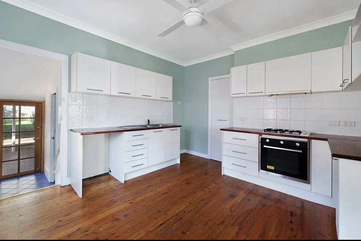 Older kitchen with white cabinetry, timber benchtops and freestanding oven