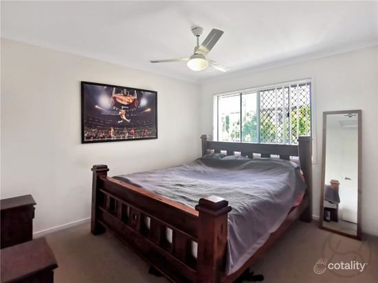 Bedroom with timber bed frame, ceiling fan and neutral walls