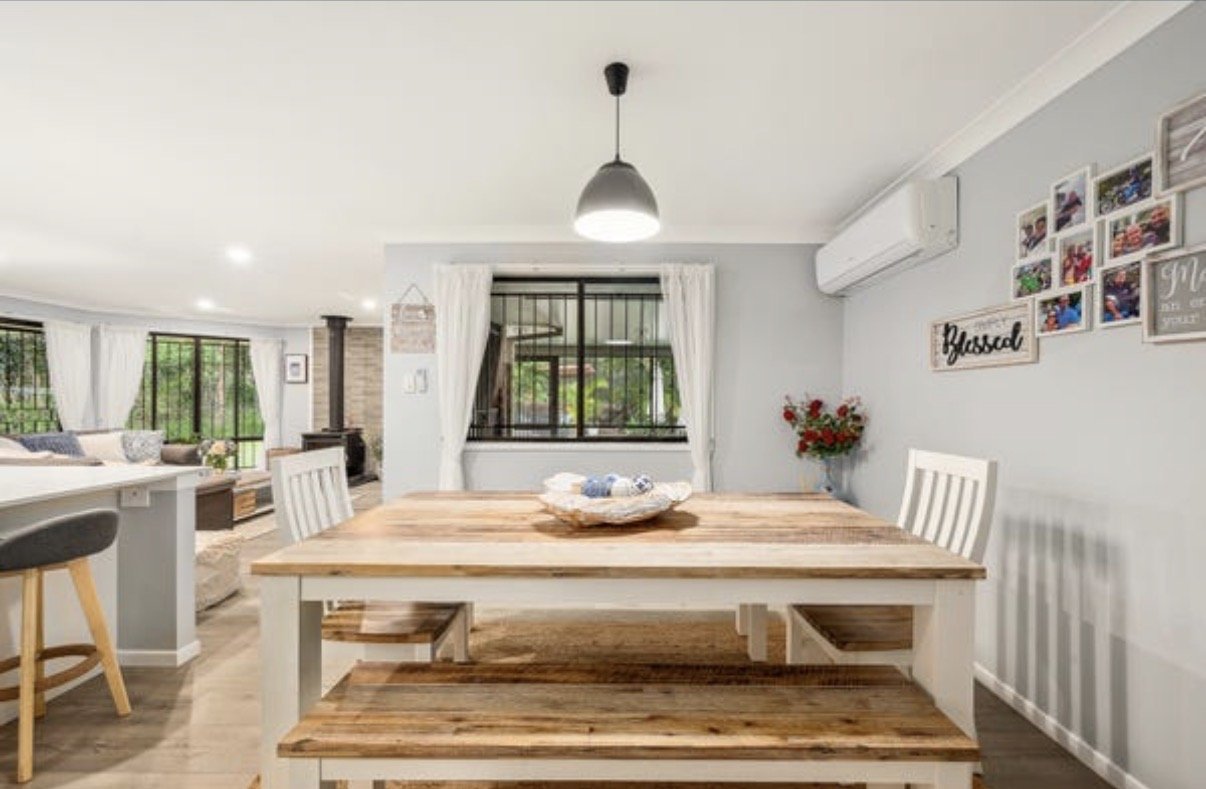 Dining space with timber table, white chairs and wall-mounted split system air conditioner
