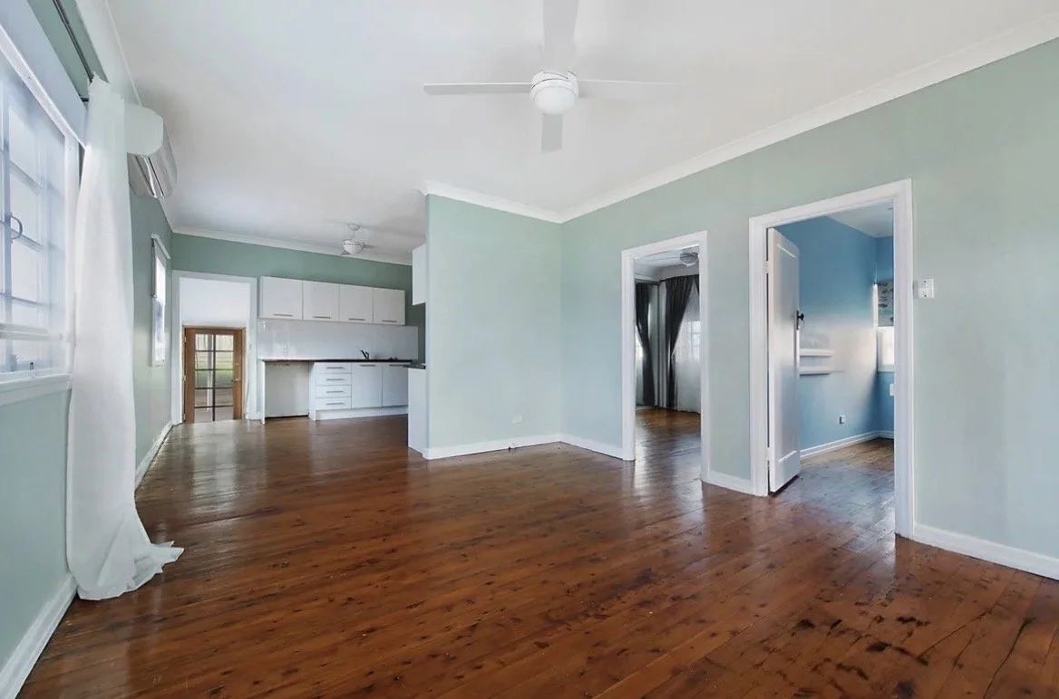 Empty living room with timber floors, green walls and ceiling fan