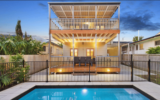 Traditional Queenslander two storey house with large patio spaces upstairs and downstairs and pool in garden