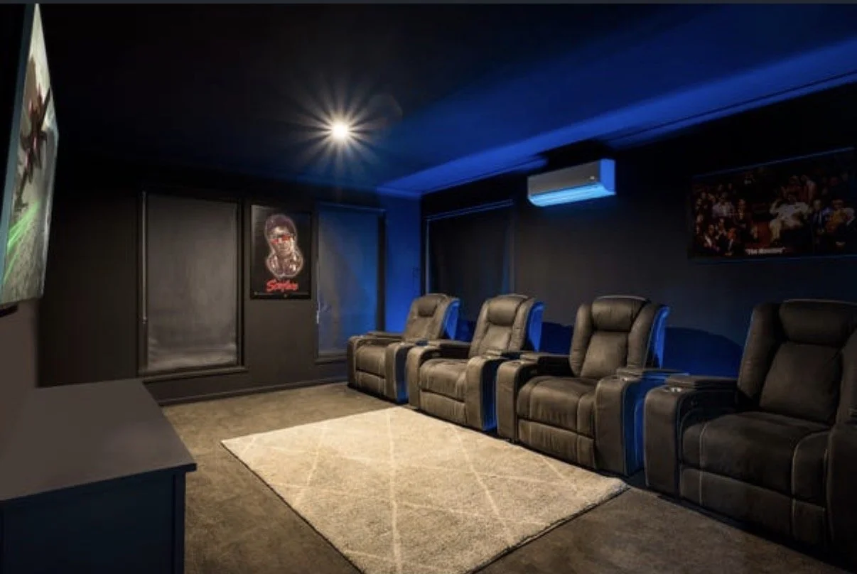 Dark home theatre with reclining leather seats, projector screen and ambient blue lighting