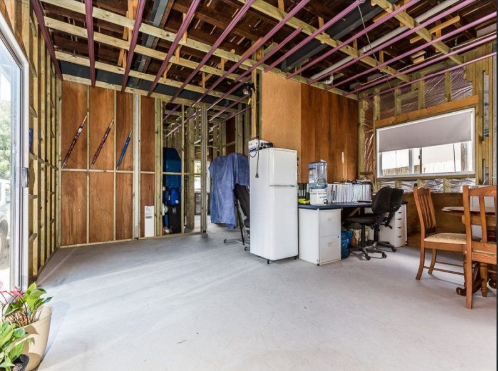 Partially stripped interior with exposed framing, concrete floor and temporary setup