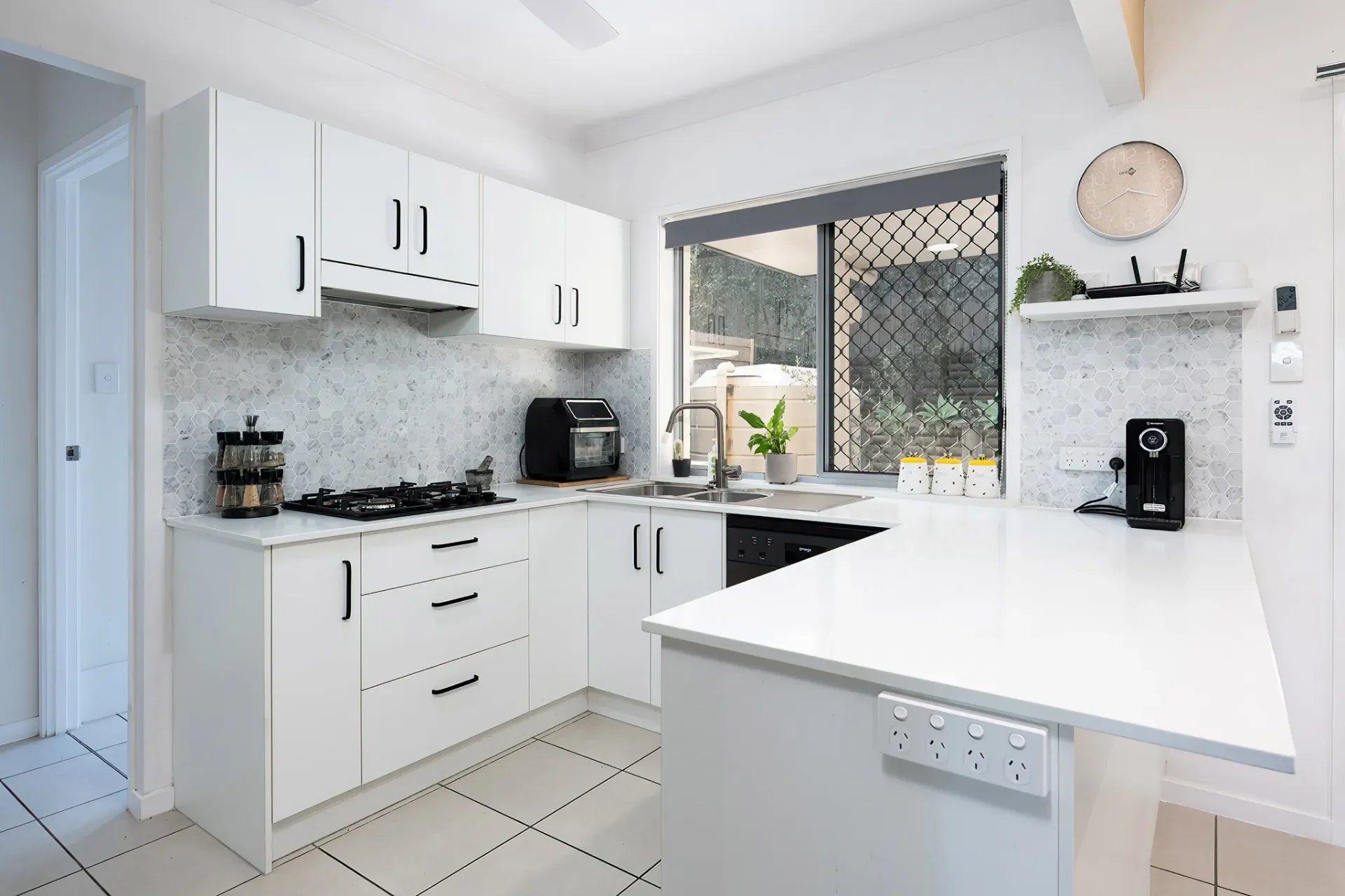 Renovated white kitchen with stone benchtops, modern cabinetry and natural light
