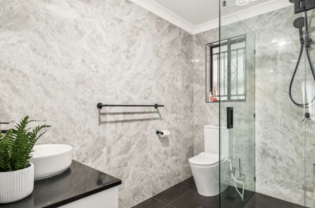 Modern bathroom with walk-in glass shower, stone-look tiles and black fixtures