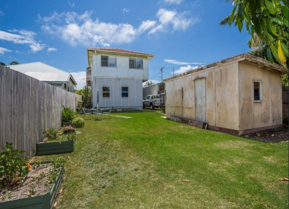 Large backyard with lawn, separate outbuilding and weathered exterior walls