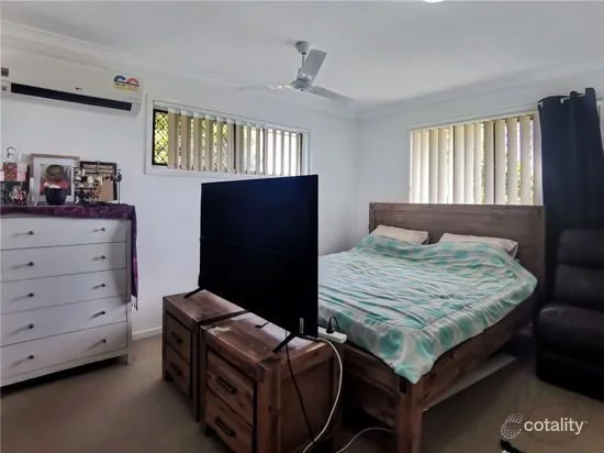 Bedroom with timber furniture, TV unit and carpet flooring