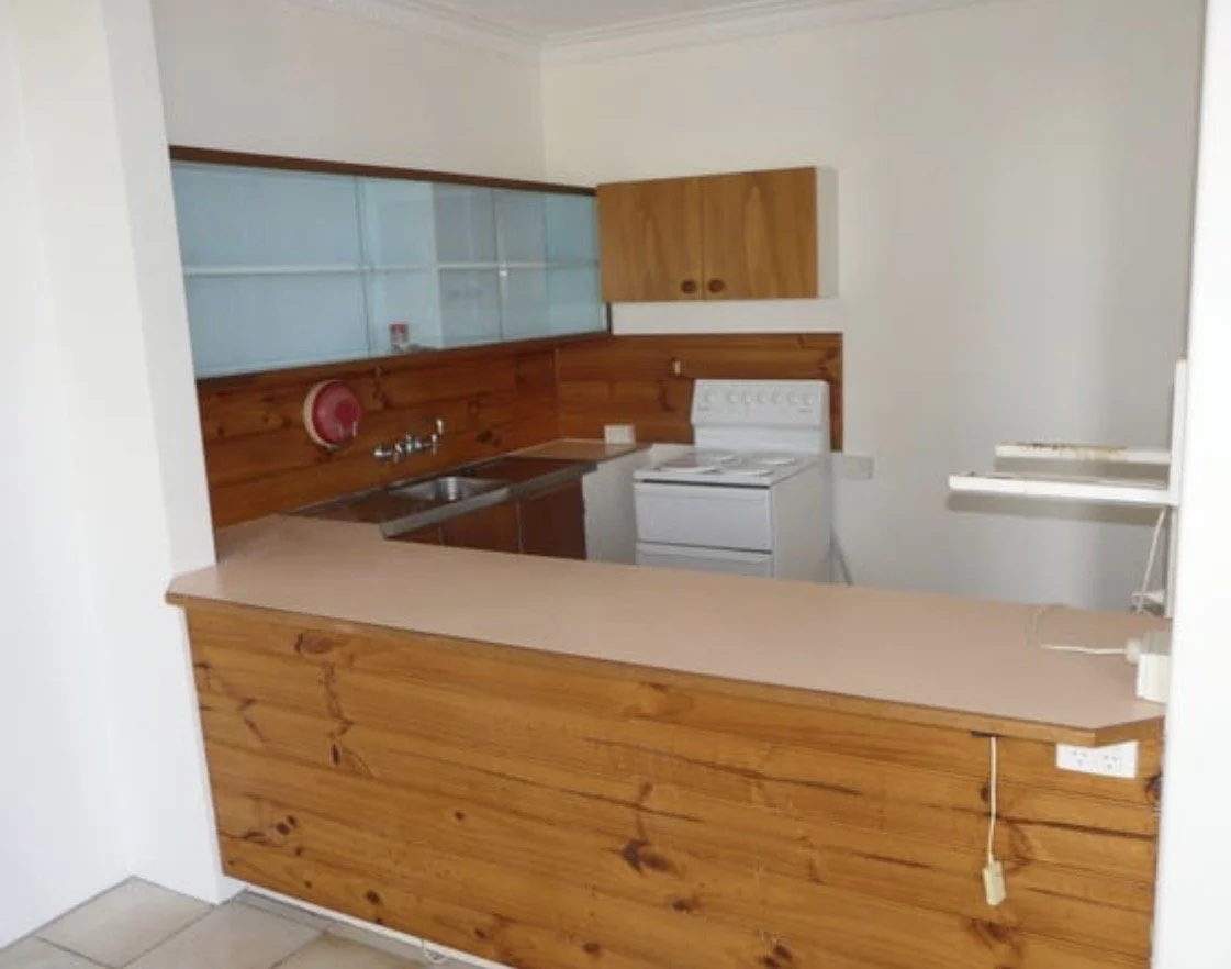Outdated kitchen with timber cabinetry, laminate benchtop and compact layout
