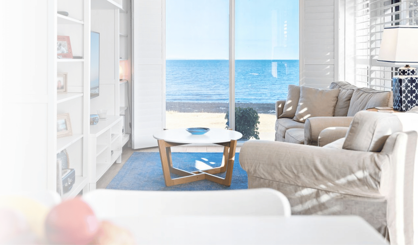 coastal, Hamptons style interior design transformation for a living room with cream linen sofas, white shelving and view over the ocean