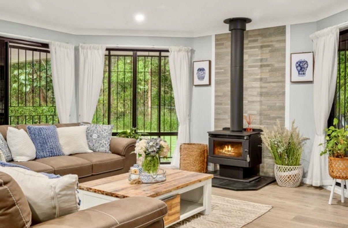 Bright living room with leather sofa, timber coffee table and modern wood-burning fireplace