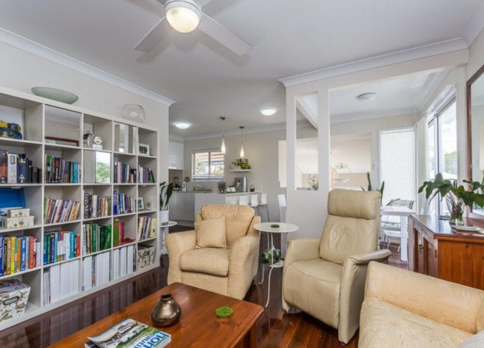 Dated living room with built-in shelving, armchairs and timber flooring