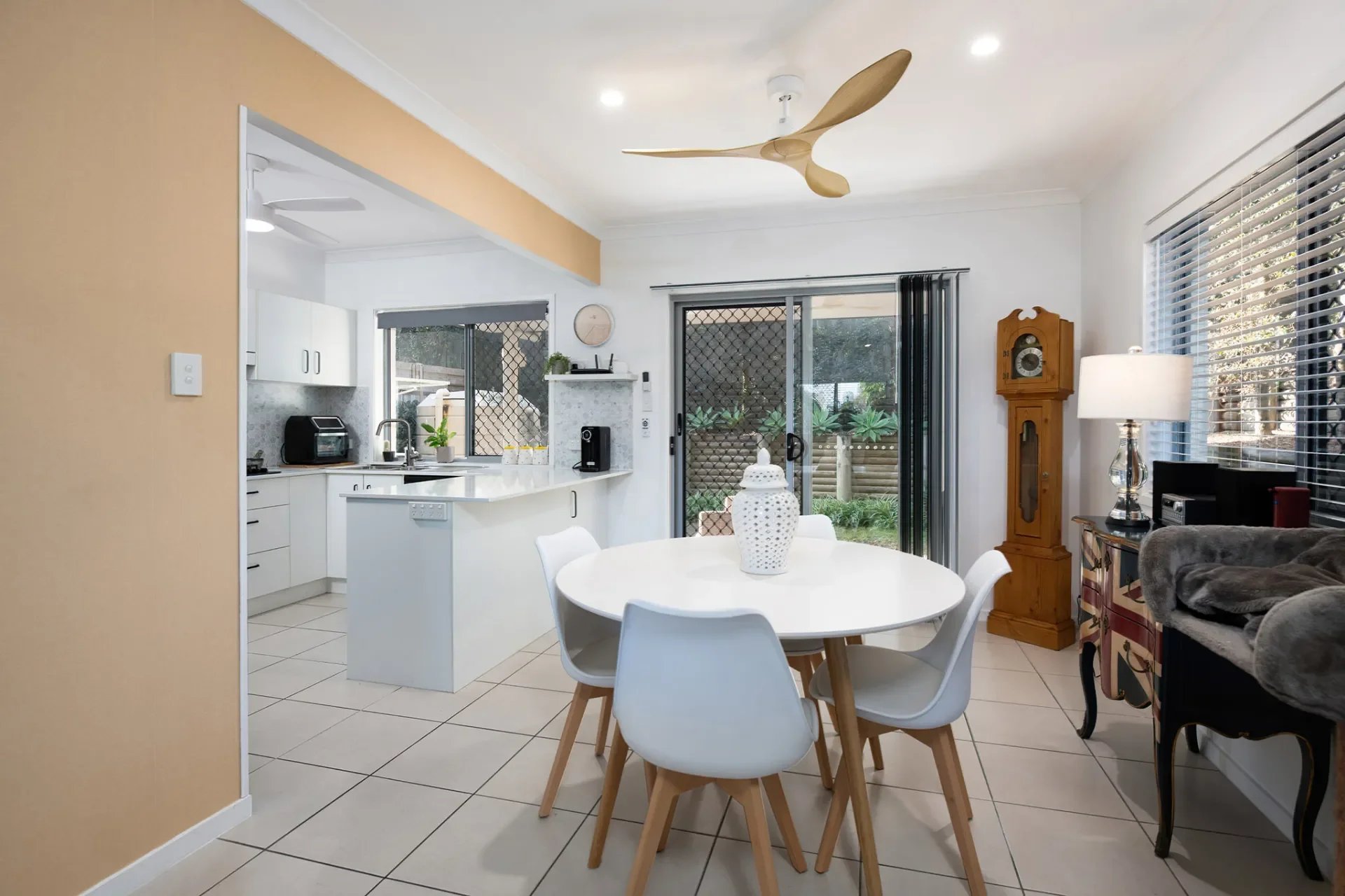 Open dining area with round table connecting to bright white kitchen