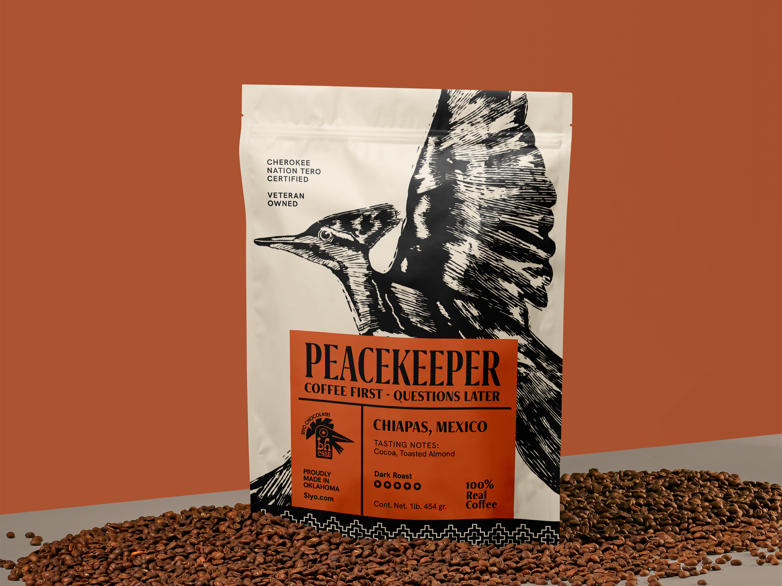 A 1-pound bag of Peacemaker Coffee from Chiapas, Mexico, featuring a black and white illustration of a bird with an elongated beak, surrounded by scattered coffee beans on a surface. The packaging indicates the coffee is dark roast, 100% real coffee, and veteran owned, GMO chocolate, and proudly made in Oklahoma.