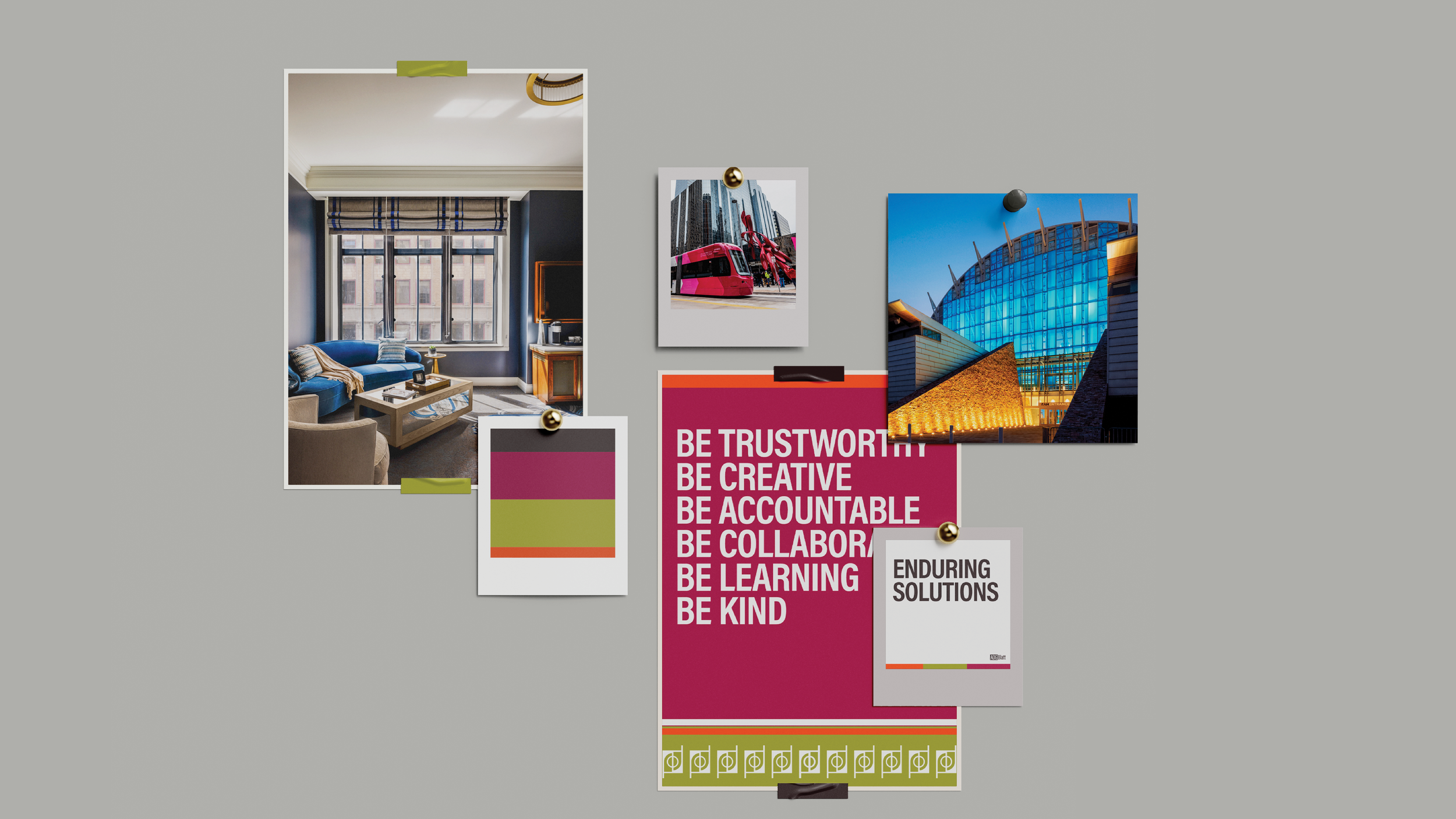 A gray wall with various photos, posters, and notes pinned to it. It includes a photo of a living room, a picture of a pink tram, an architectural photo of a modern building, and a poster with words like 'Be Trustworthy,' 'Be Creative,' 'Be Accountable,' 'Be Collaborate,' 'Be Learning,' and 'Be Kind.' There's also a smaller dark pink and green note, and a white card labeled 'Enduring Solutions'.