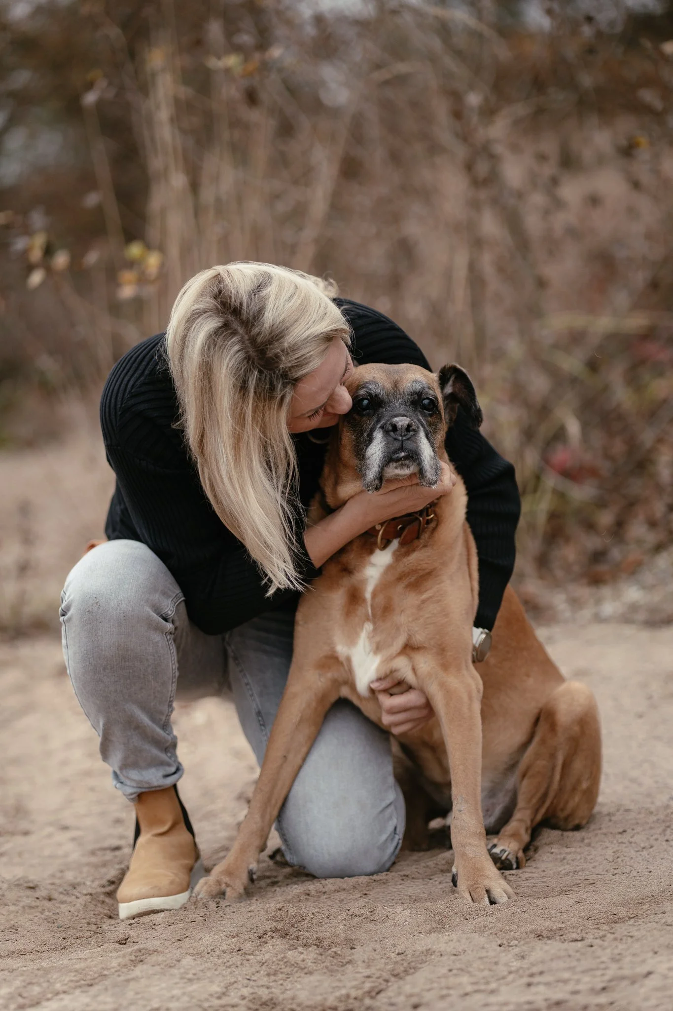 Frau umarmt liebevoll einen großen Boxer-Mischling.