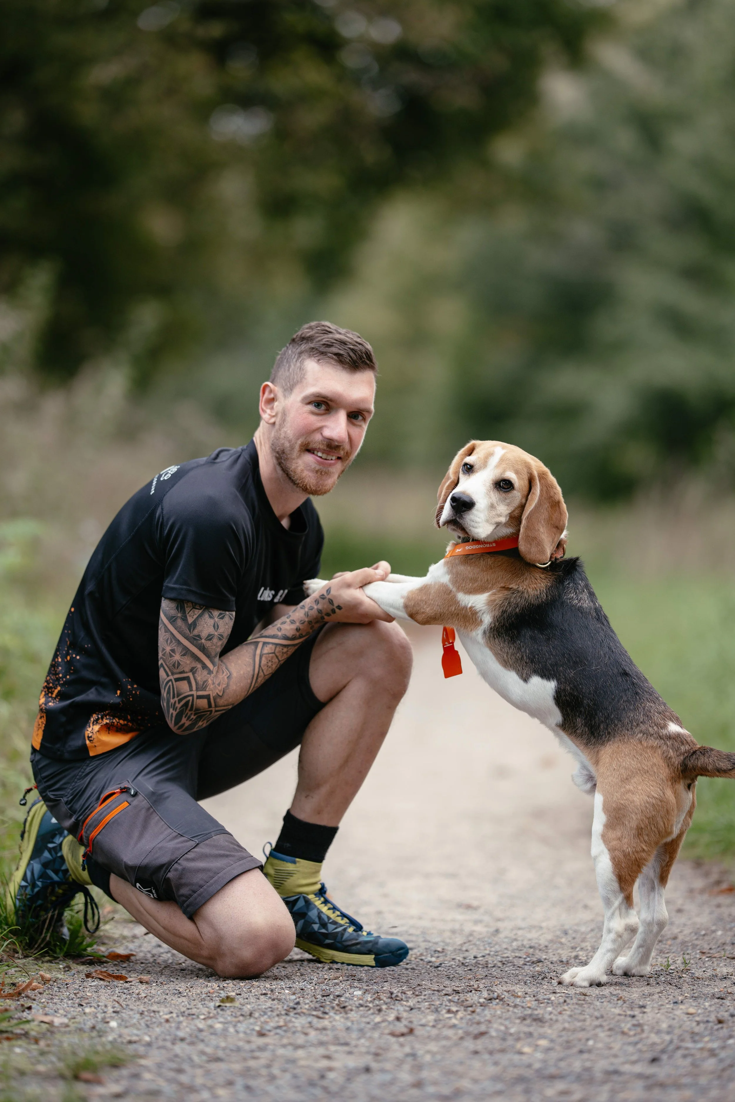 Ein Mann hält glücklich die Pfoten seines Beagle Rüden. 