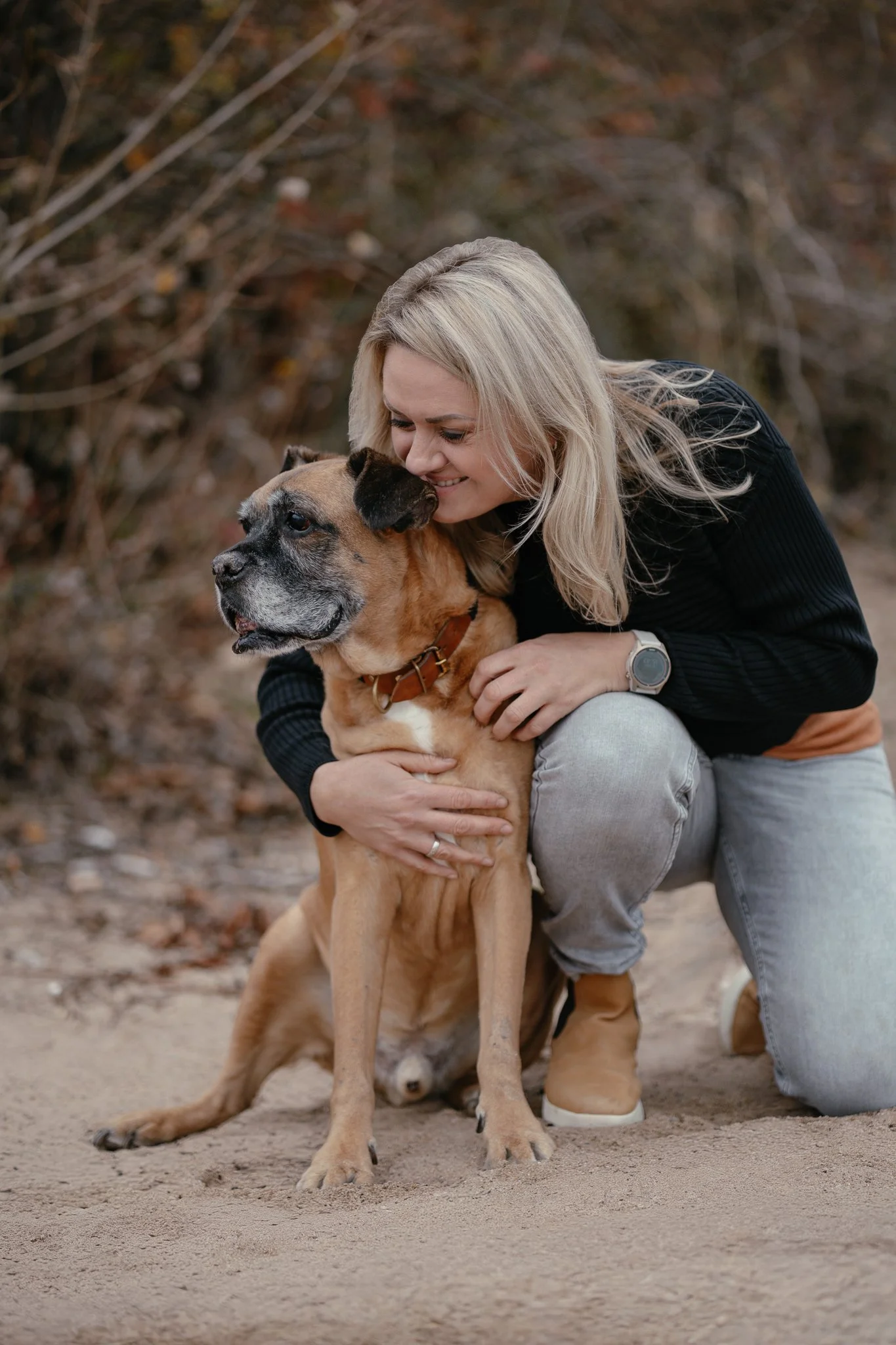 Frau umarmt ihren Hund und lächelt.