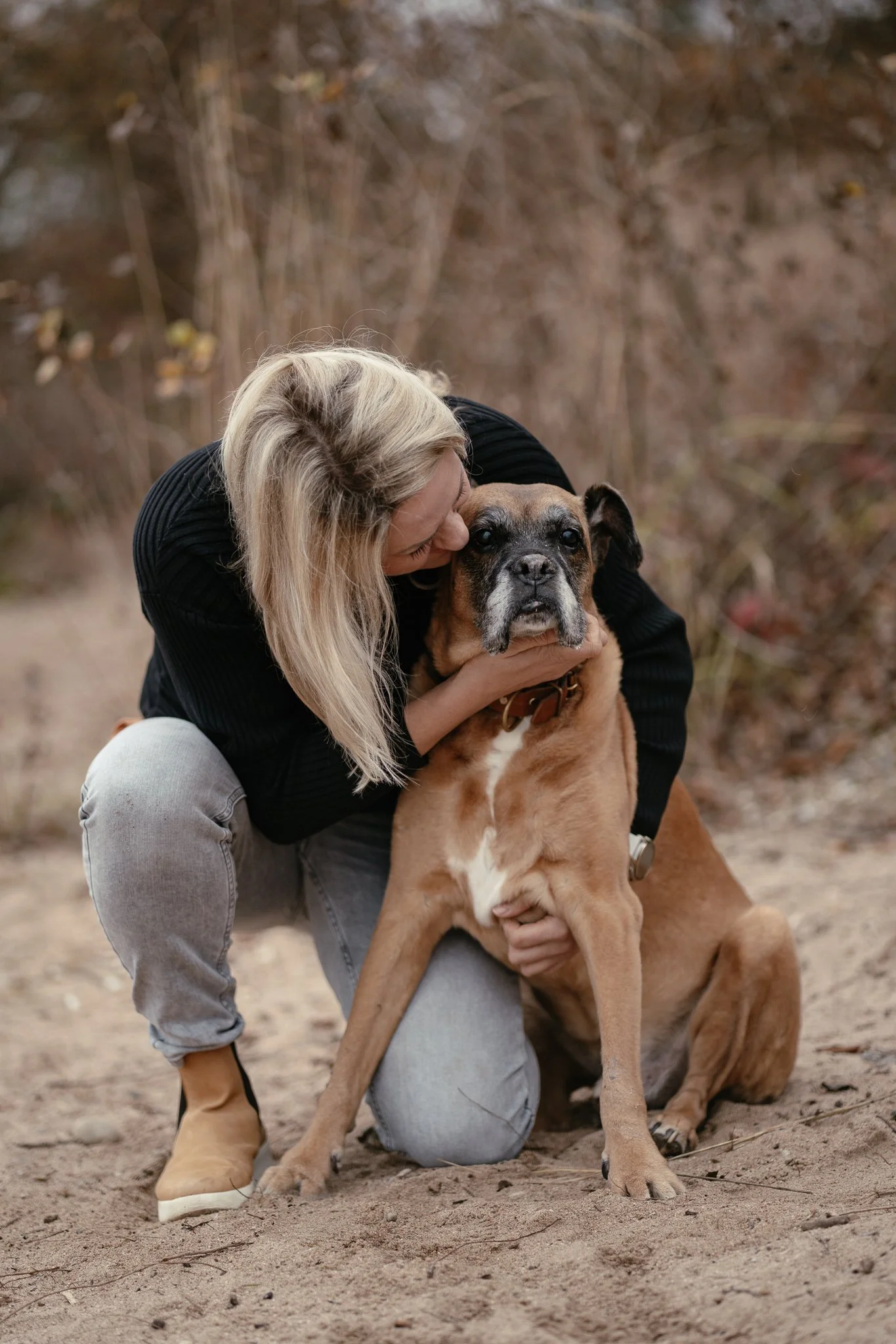 Frau umarmt liebevoll einen großen Boxer-Mischling.