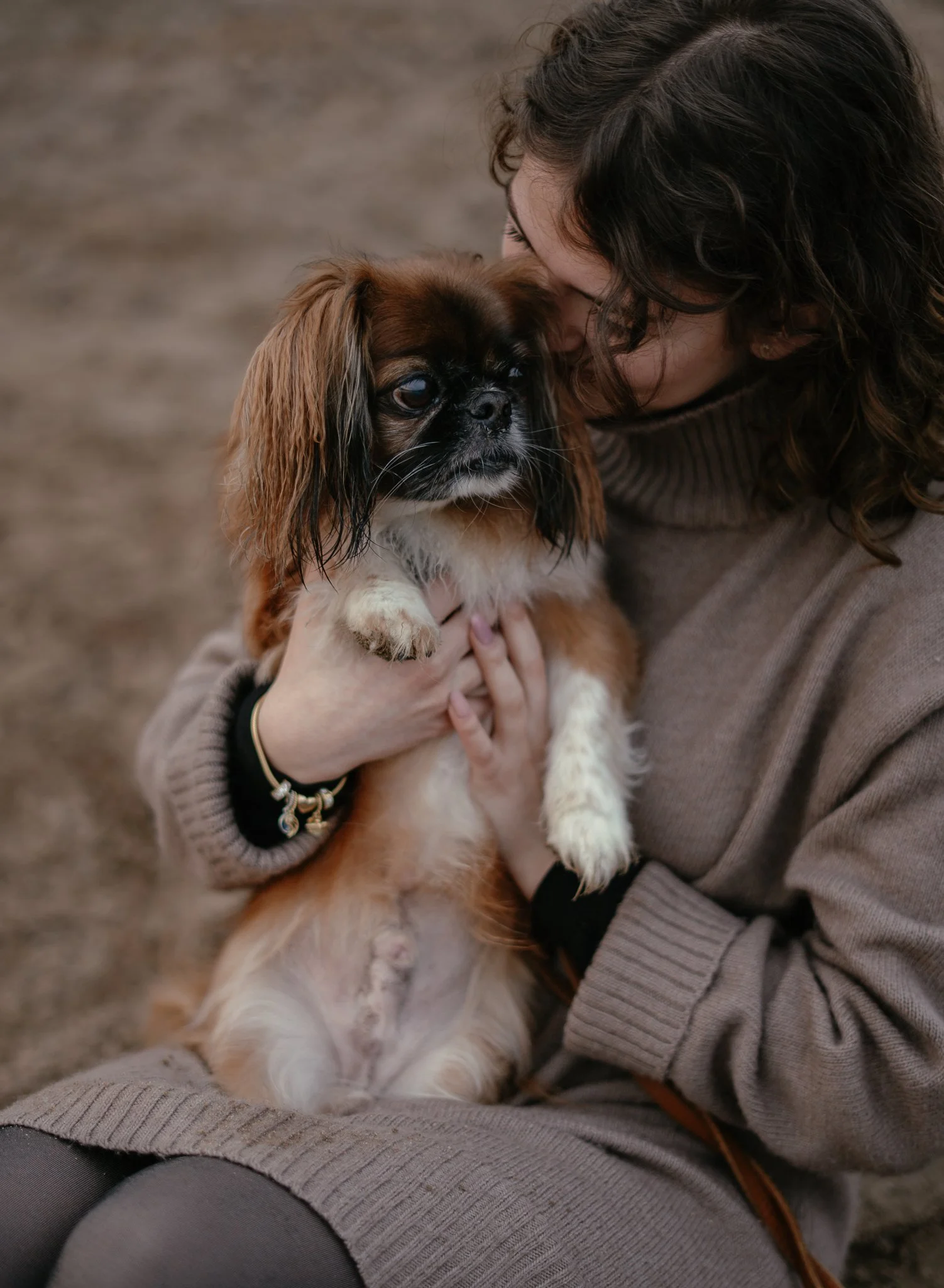 Eine Frau hält einen kleinen Mischlingshund in den Armen, während sie sich liebevoll an ihn lehnt.