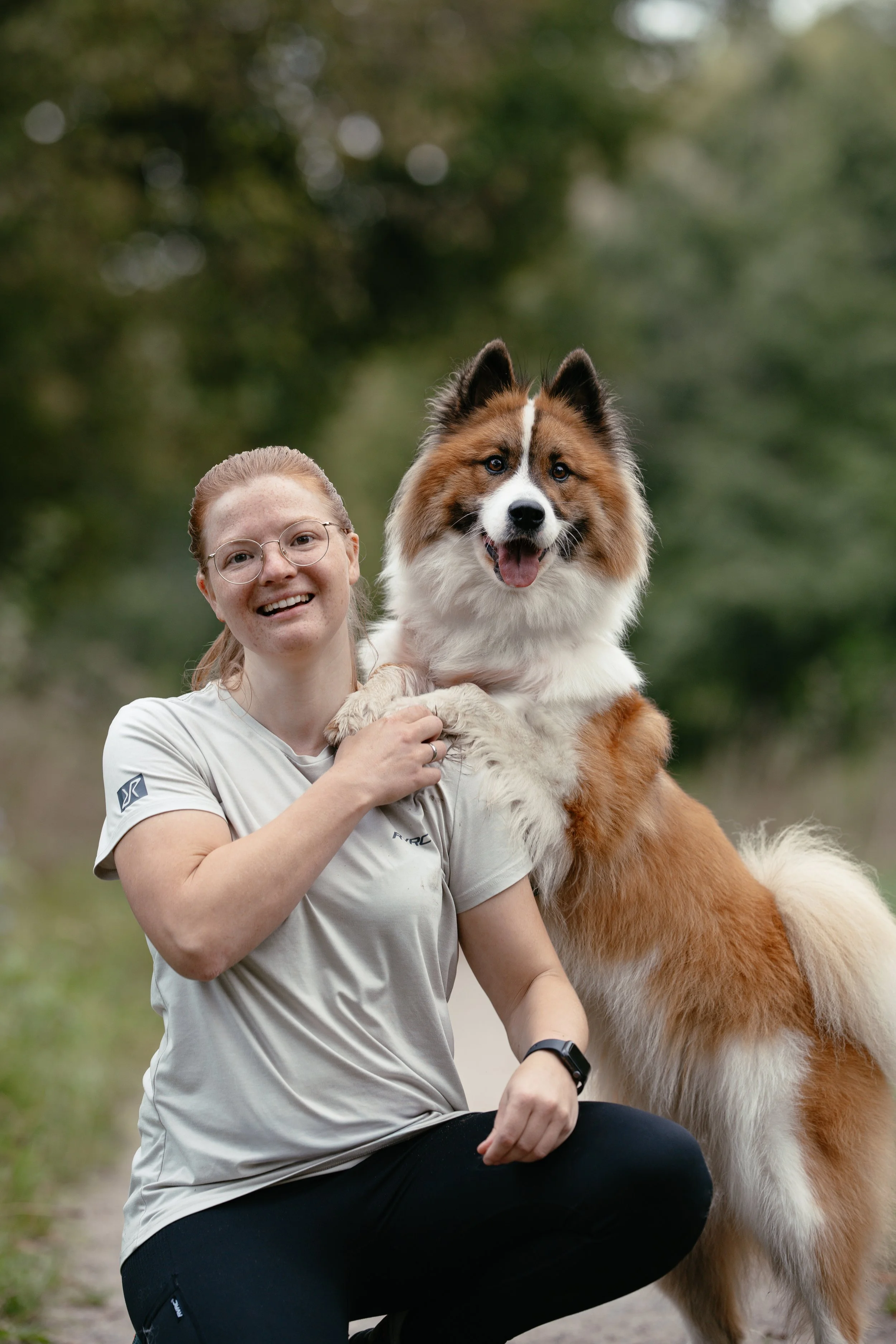Eine Frau kniet und ihre Elo Hündin schaut über ihre Schulter.