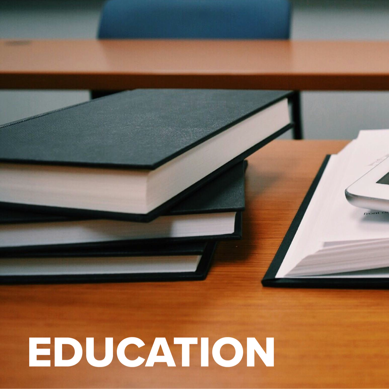 Stack of black-covered notebooks and an open folder with papers on a wooden desk, with the word 'Education' written in white at the bottom of the image.
