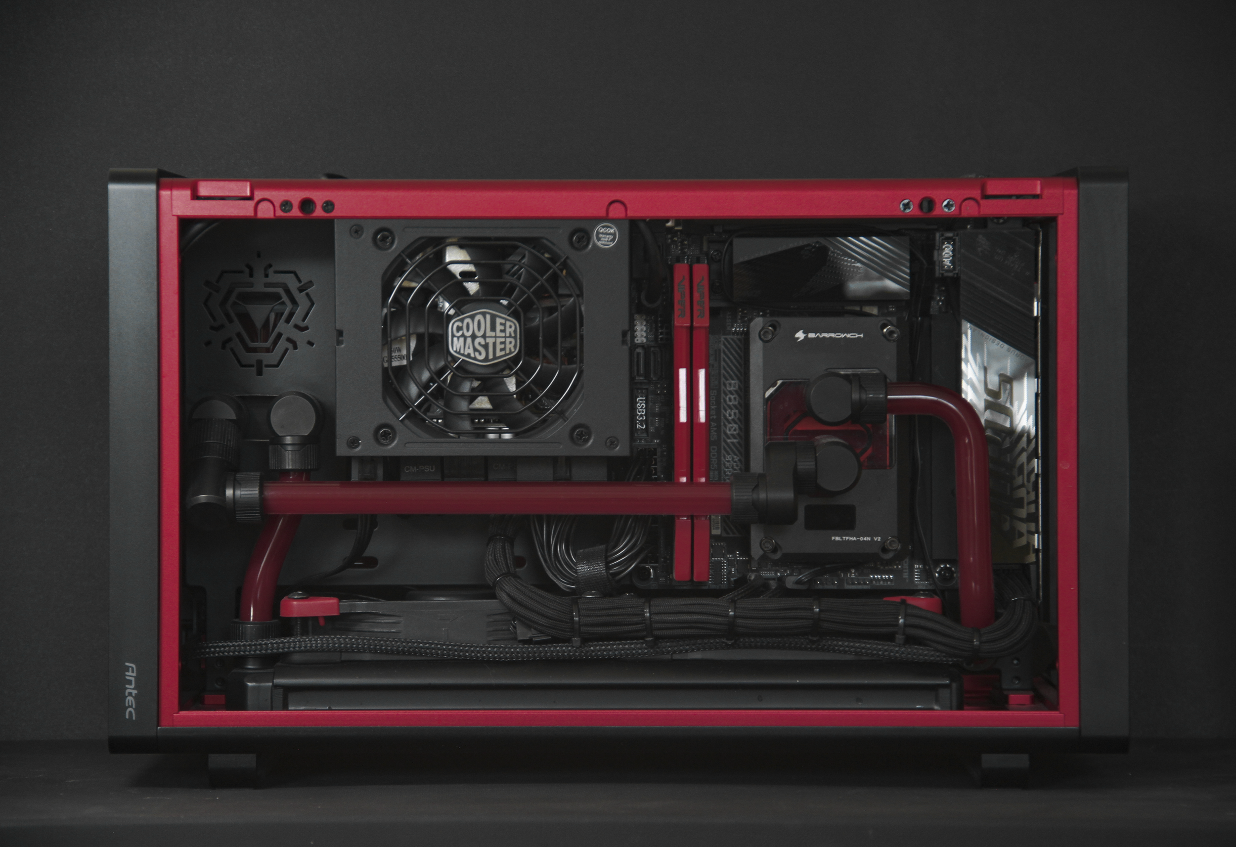 Inside a custom-built gaming computer with a red and black color scheme, showing a water cooling system, power supply, and motherboard.