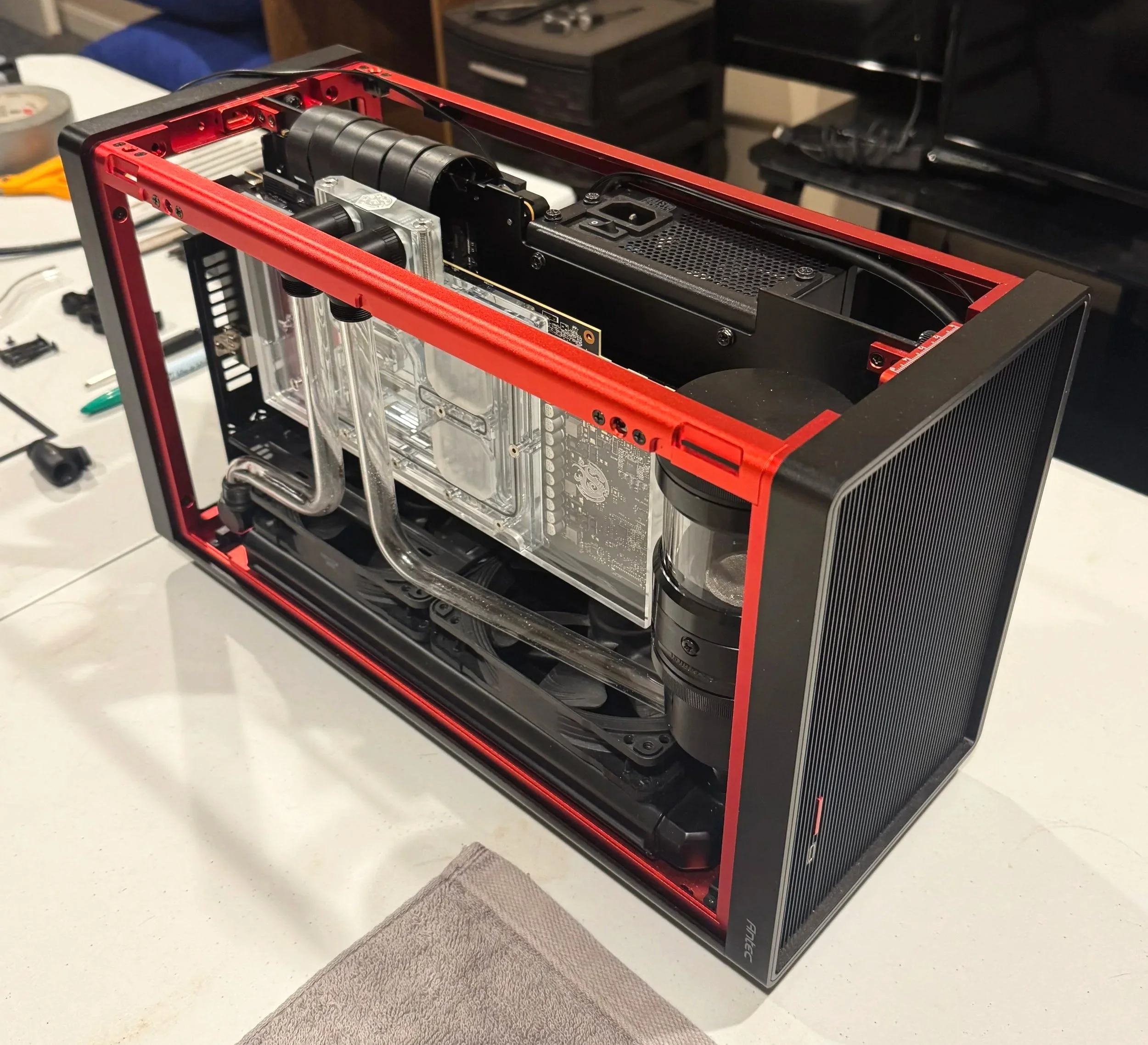 A custom-built high-end PC with a water cooling system, featuring a black and red frame, transparent side panel, and visible liquid cooling tubes.