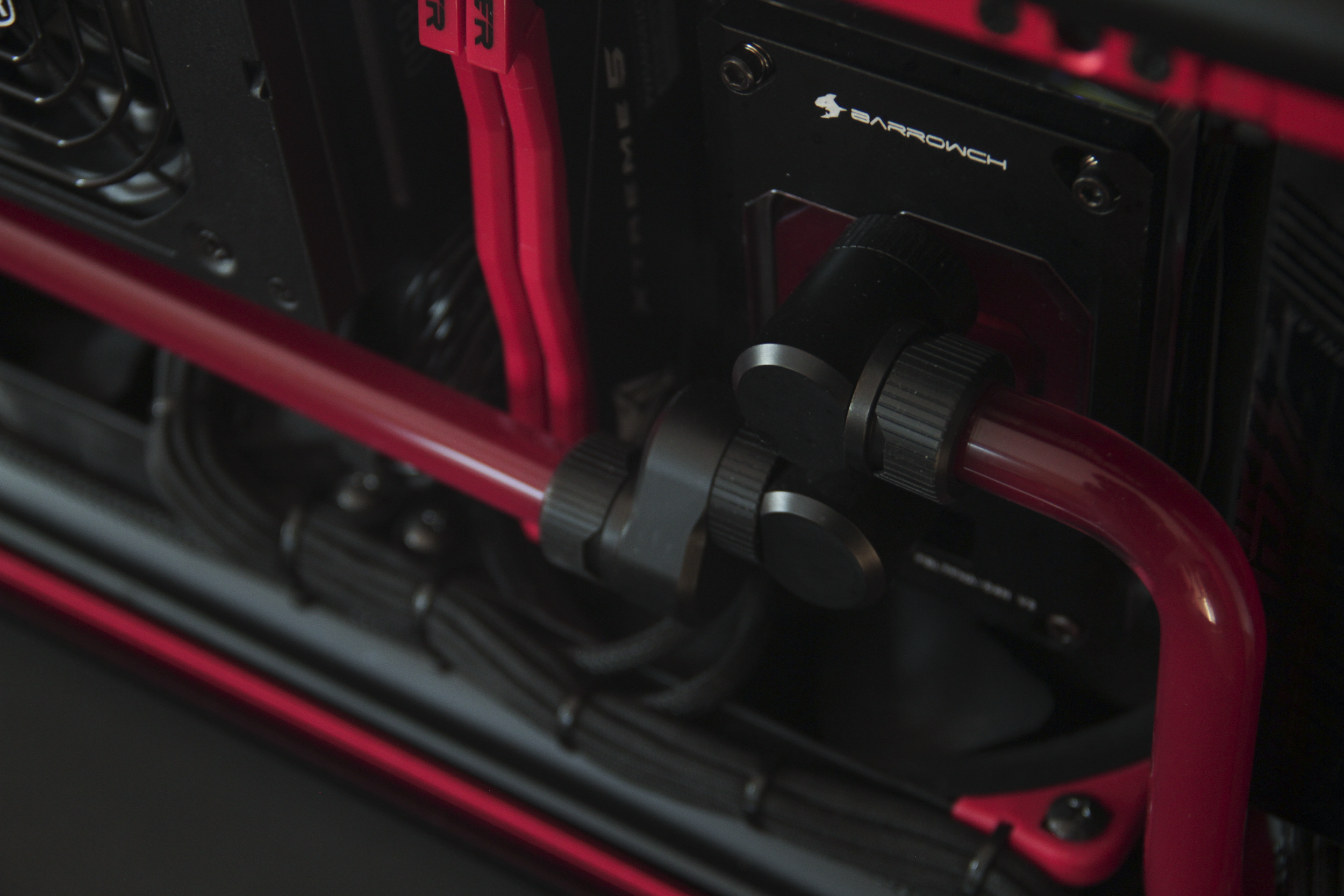 Close-up of a gaming computer's interior showing red coolant tubes and a black water cooling reservoir with the brand Arrowch visible.