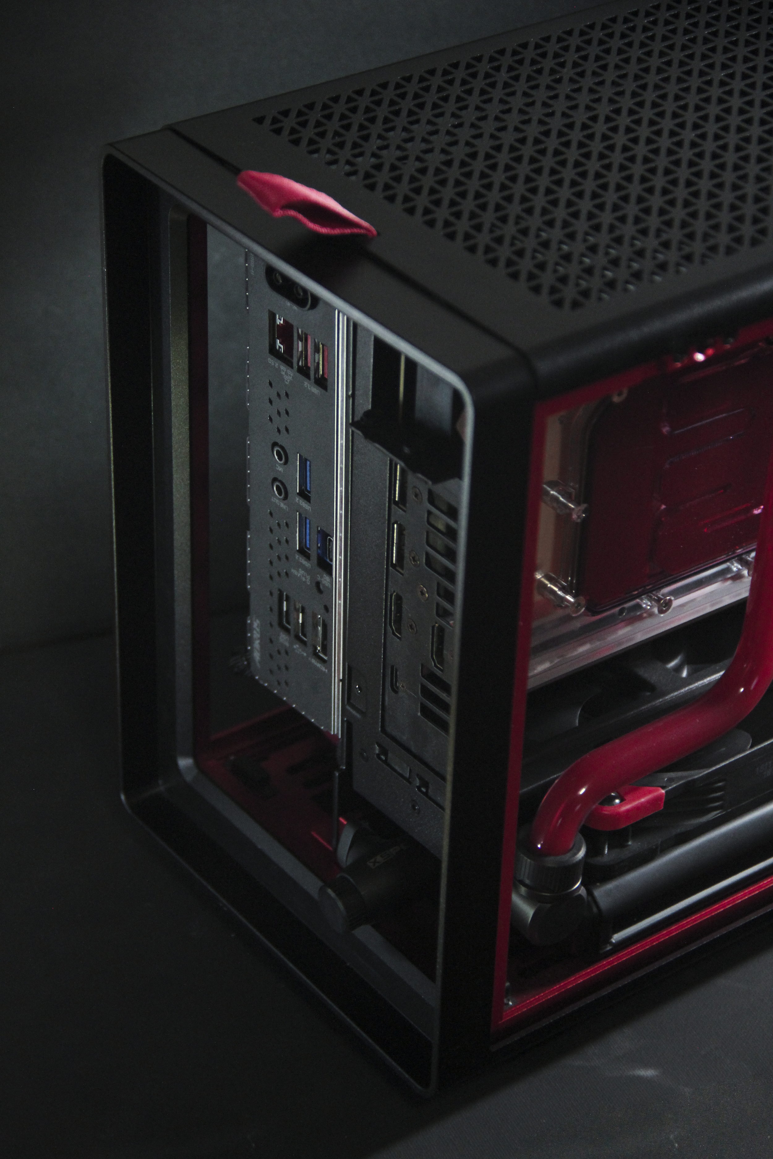 Close-up of a custom-built gaming or workstation computer with a transparent side panel showing internal components including a liquid cooling system with red tubes, and front I/O ports.