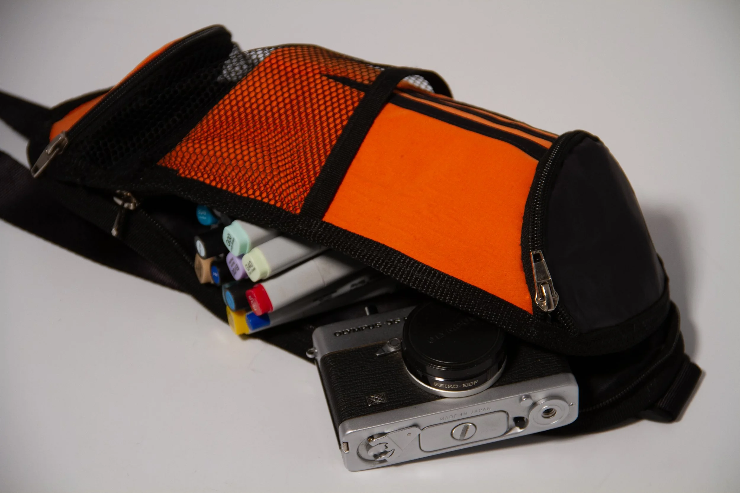 Camera bag open with markers and a vintage camera inside