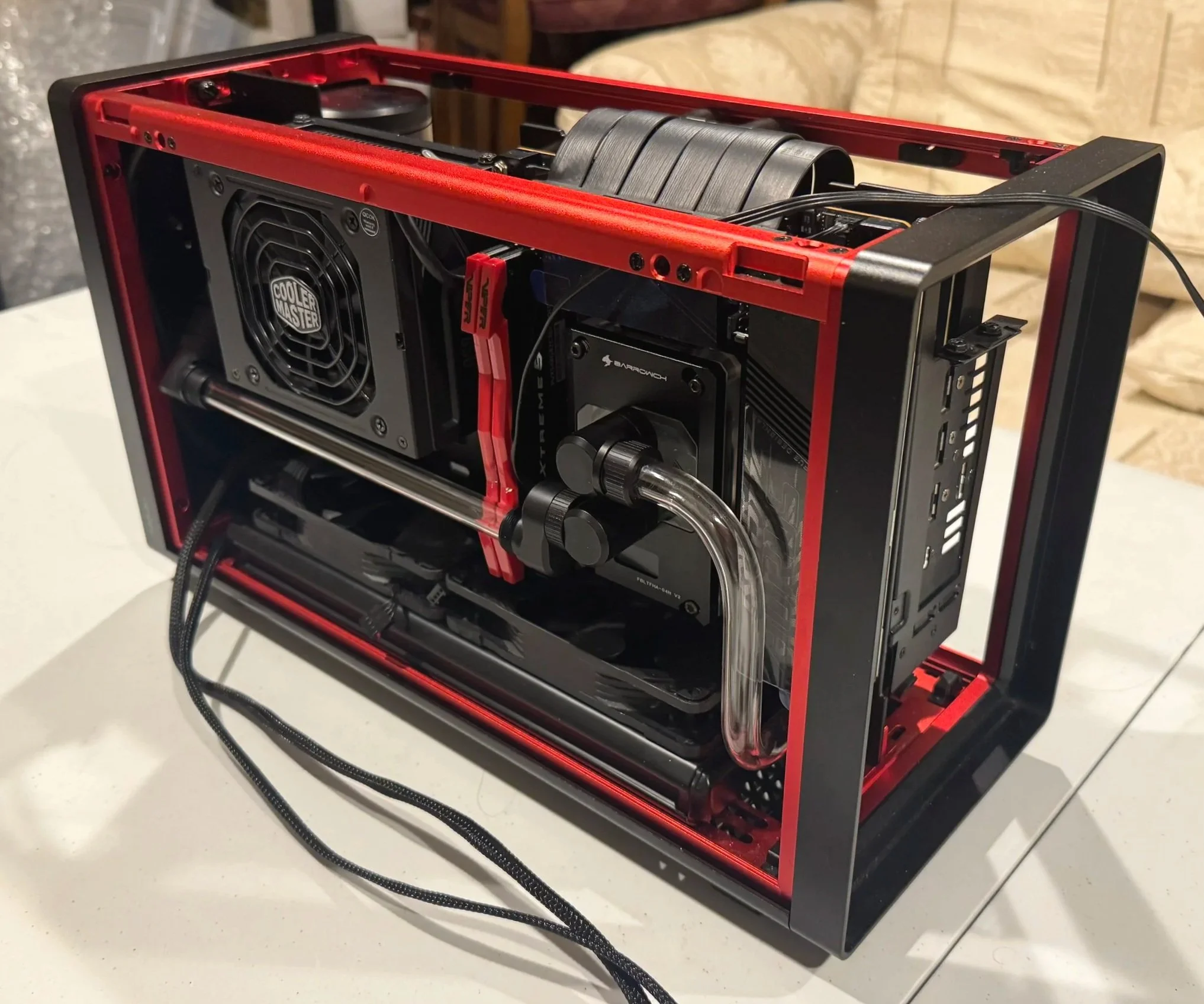 Open custom-built gaming computer with water cooling system, black and red color scheme, mounted components, and transparent tubes.