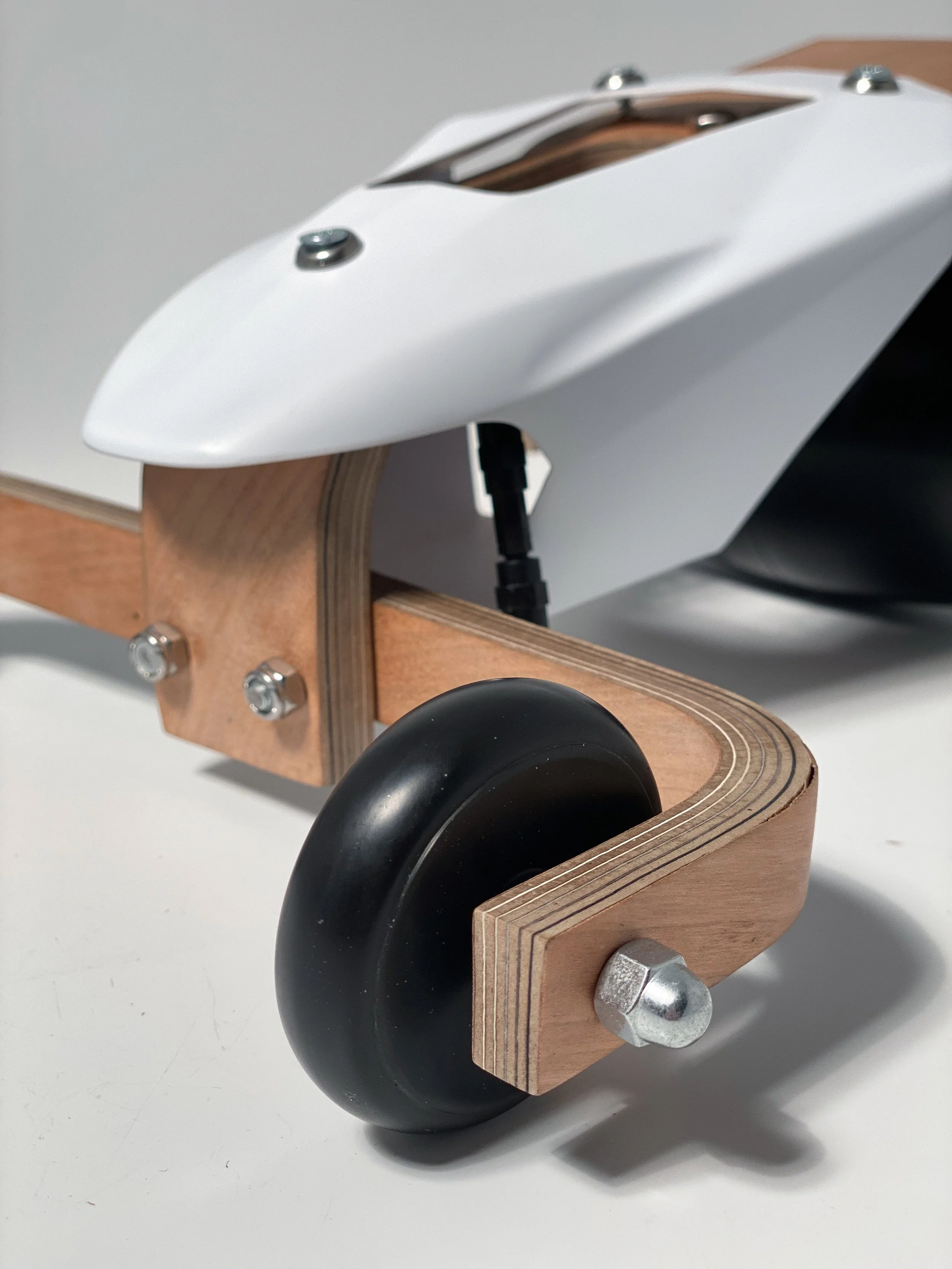 A model of a race car with a sleek white body, mounted on a wooden chassis with black wheels.