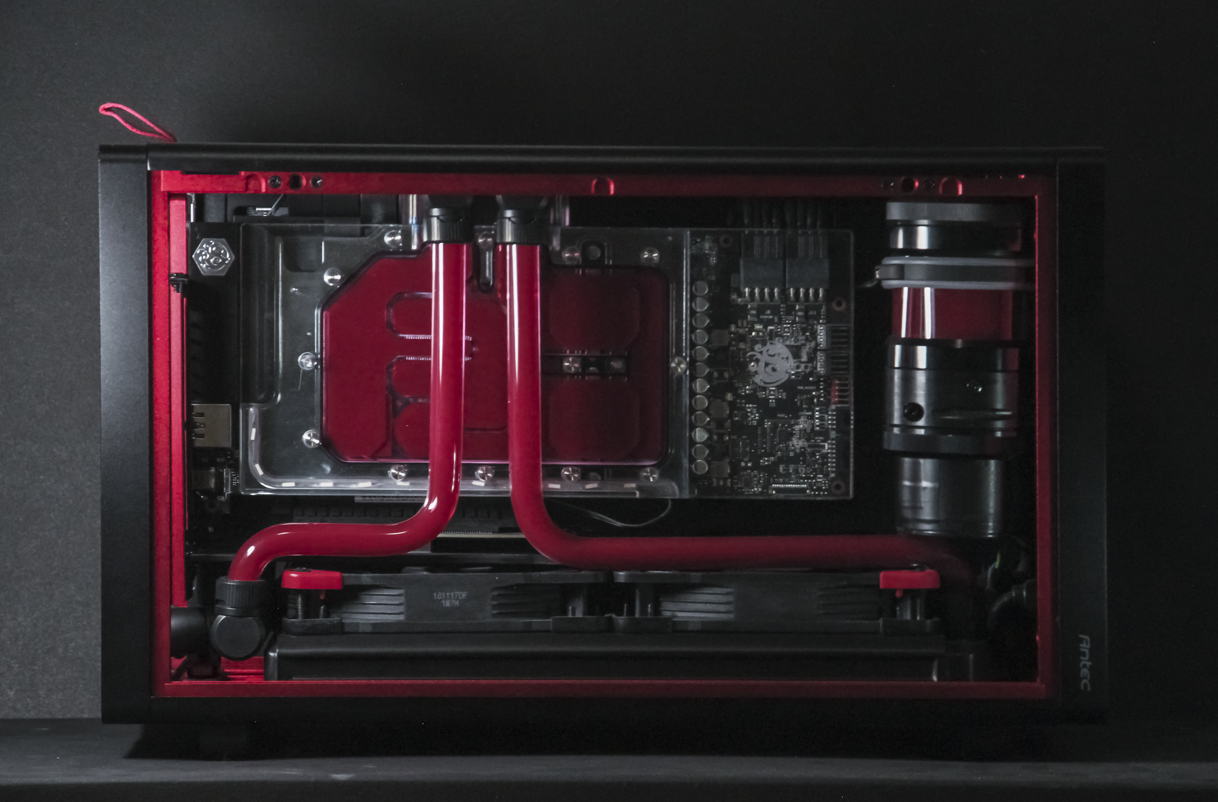 Top-down view of a custom computer with a liquid cooling system, including red coolant tubes, a water block, and visible internal components.