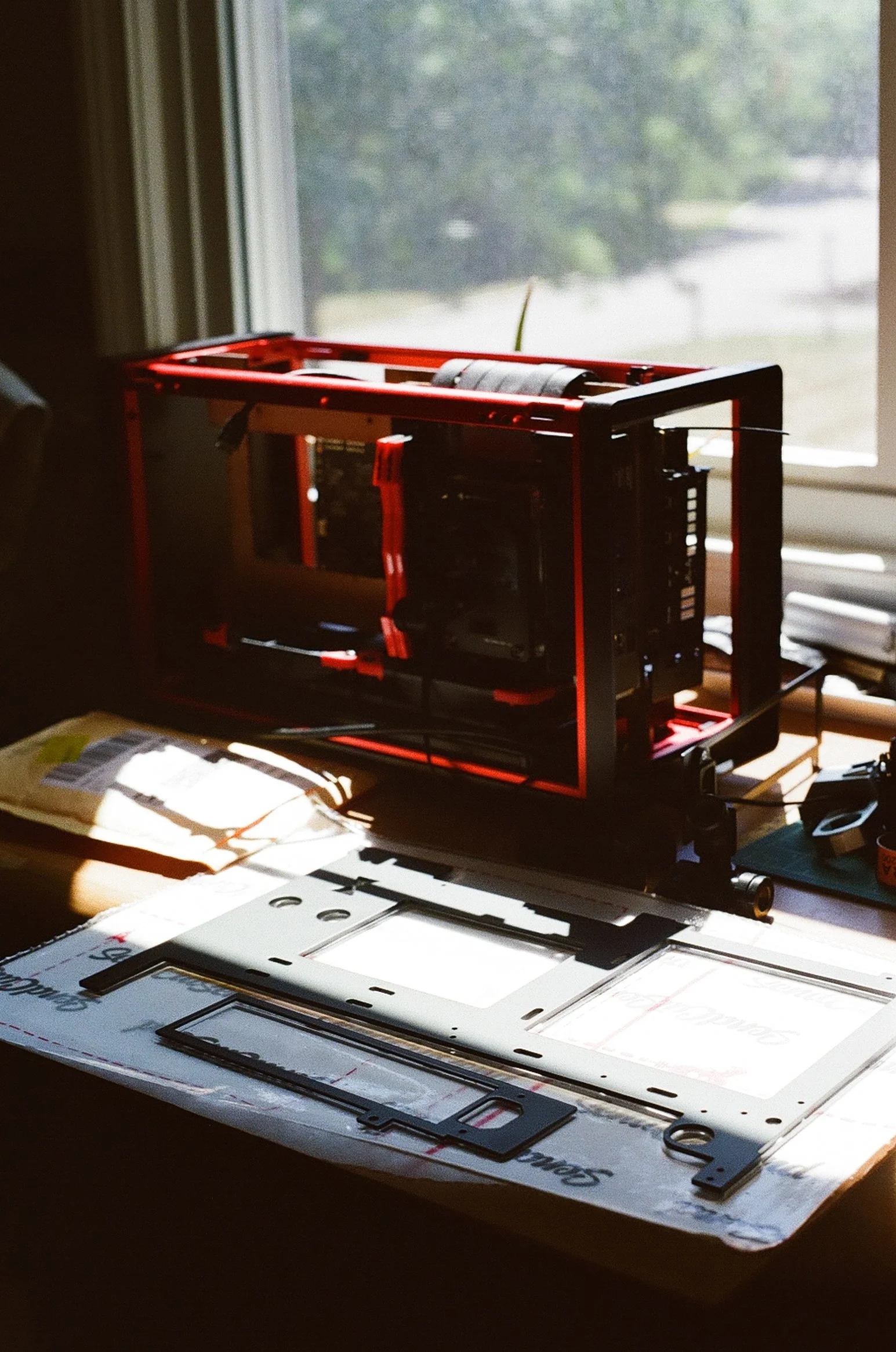 Open computer case with parts on a desk, illuminated by natural light from a window.