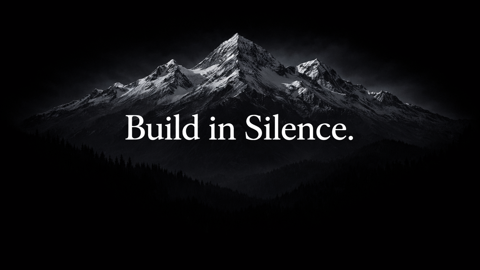 Snow-capped mountain range under dark sky with the phrase 'Build in Silence.' in white text.