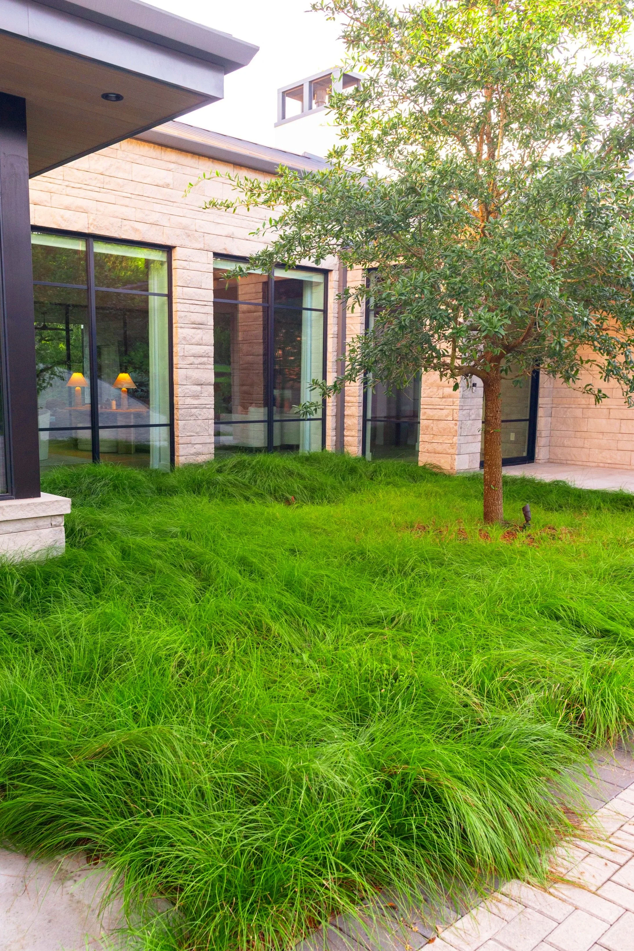 The sedges were planted in soft, sculptural mounds to create a lush, layered green view from the entry windows, bringing the garden experience inside the home.