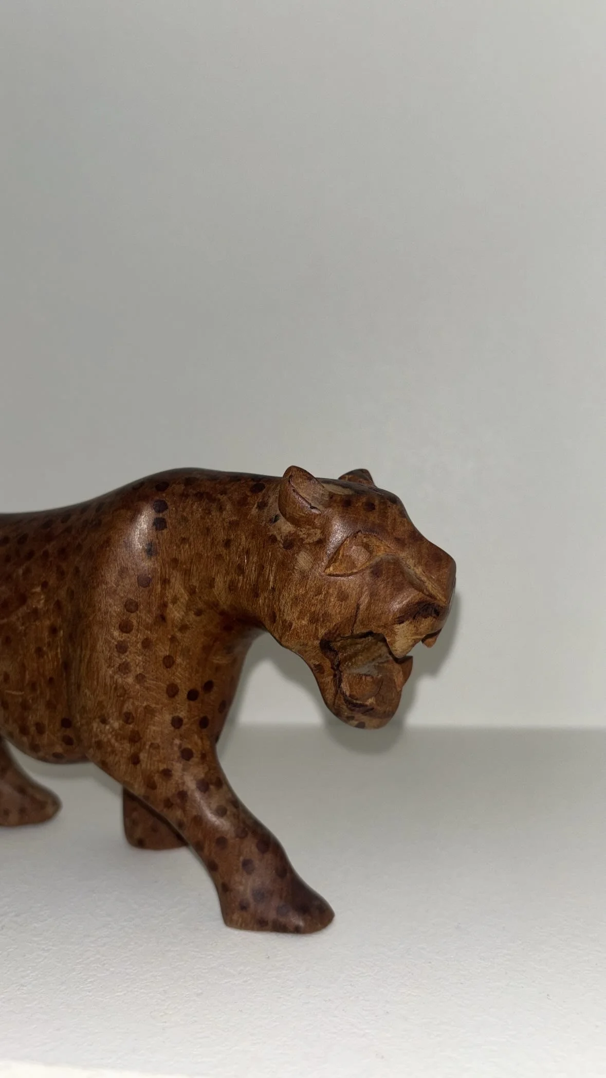 A carved wooden elephant figurine placed on a white surface against a plain white background.