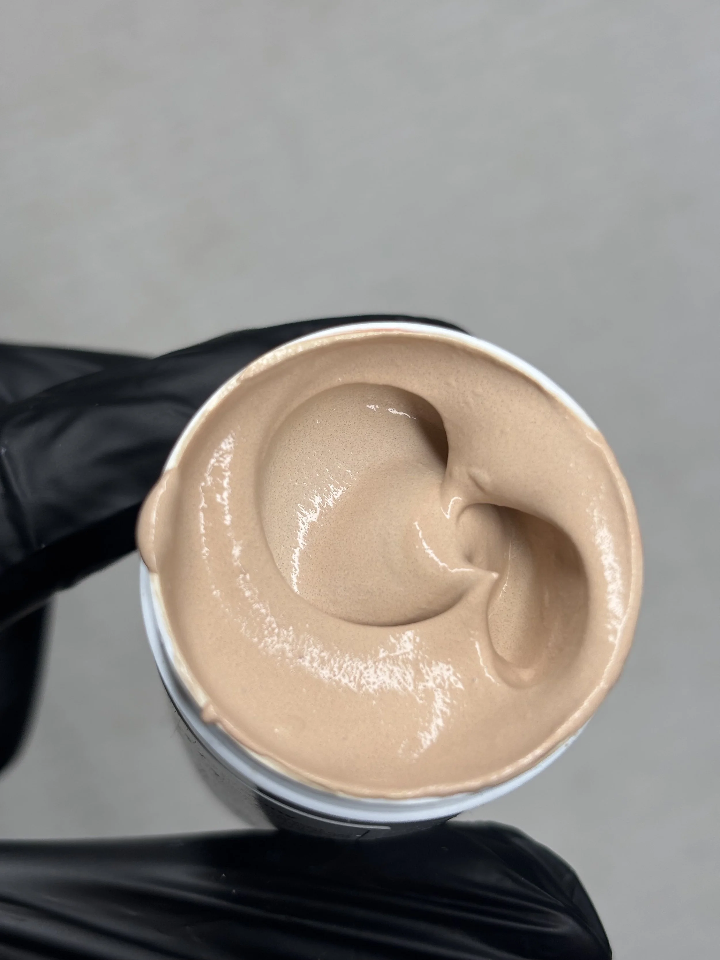 A top-down view of a cup of coffee with foam, held by someone wearing black clothing.