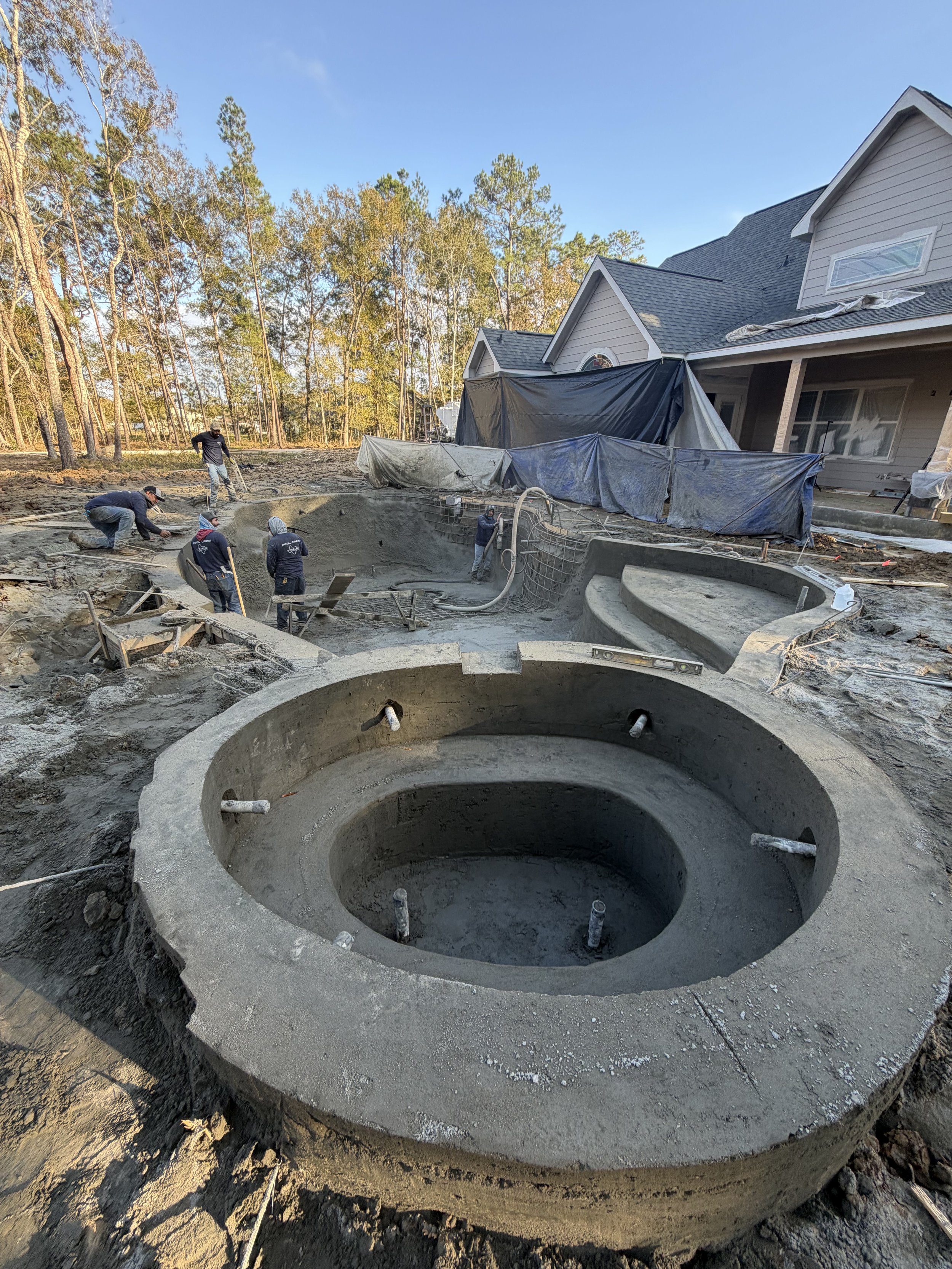 Construction workers building a concrete hot tub in a backyard.