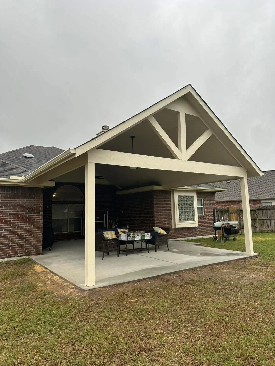 Backyard patio with covered roof, outdoor furniture, BBQ grill, and a grassy yard area.