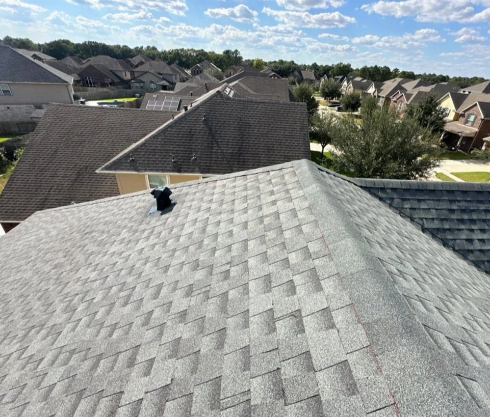 View of multiple house rooftops in a suburban neighborhood under a partly cloudy sky.