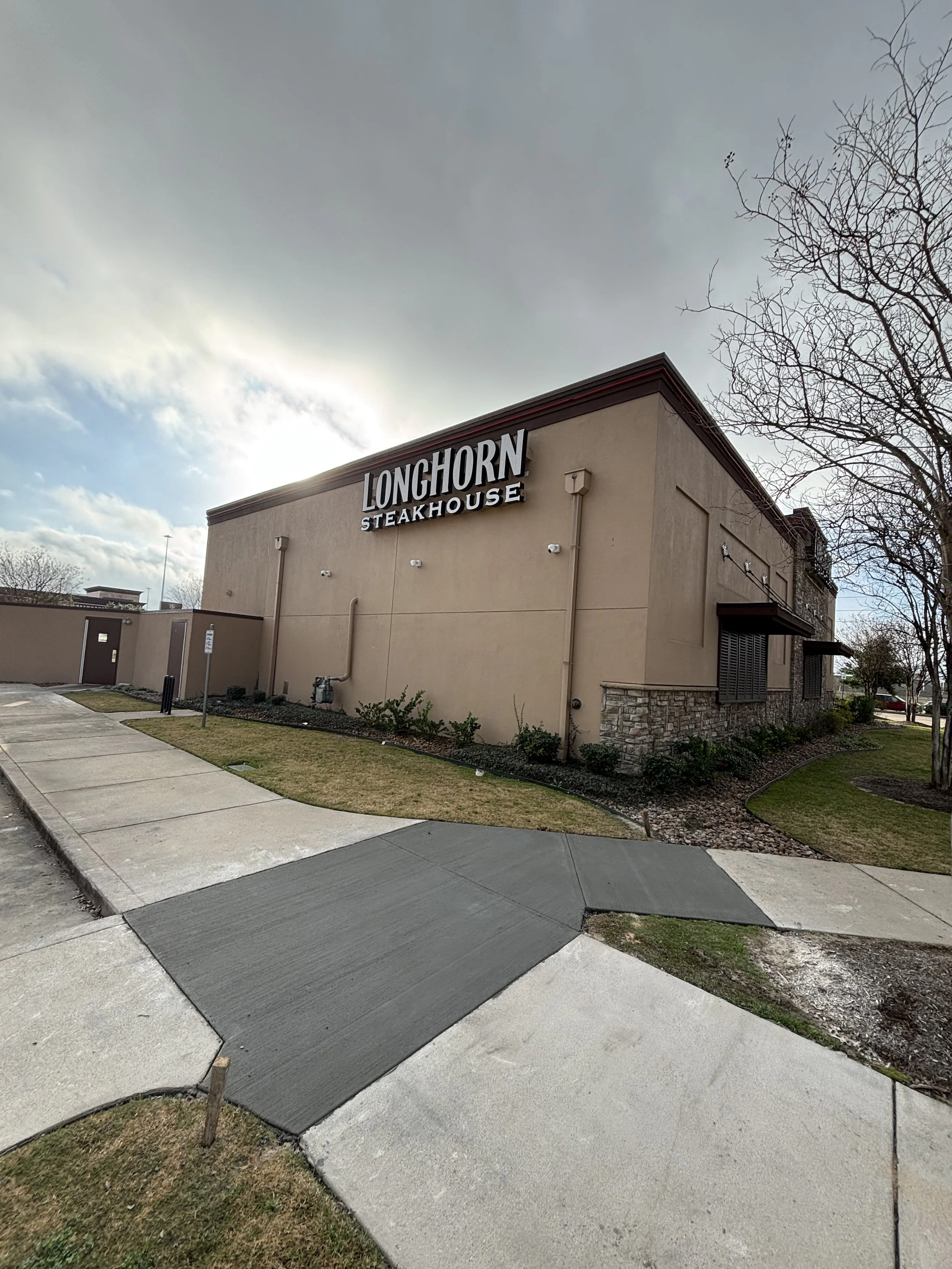 Exterior view of LongHorn Steakhouse building with sidewalk and landscaping