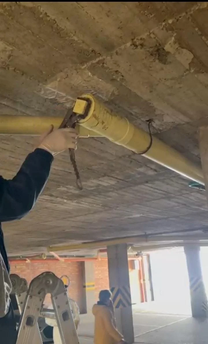 Persona instalando una tubería en el techo de un estacionamiento.