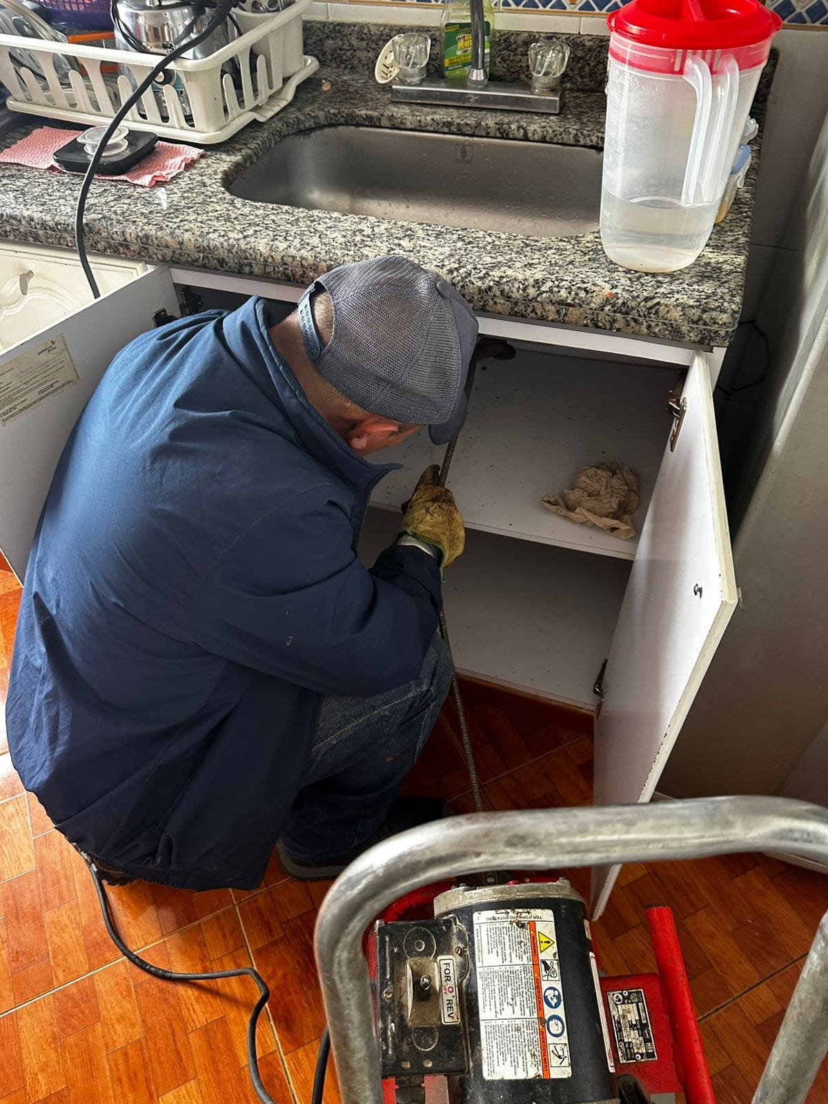 Una persona sondeando una cosina para destapar la tuberia tapada