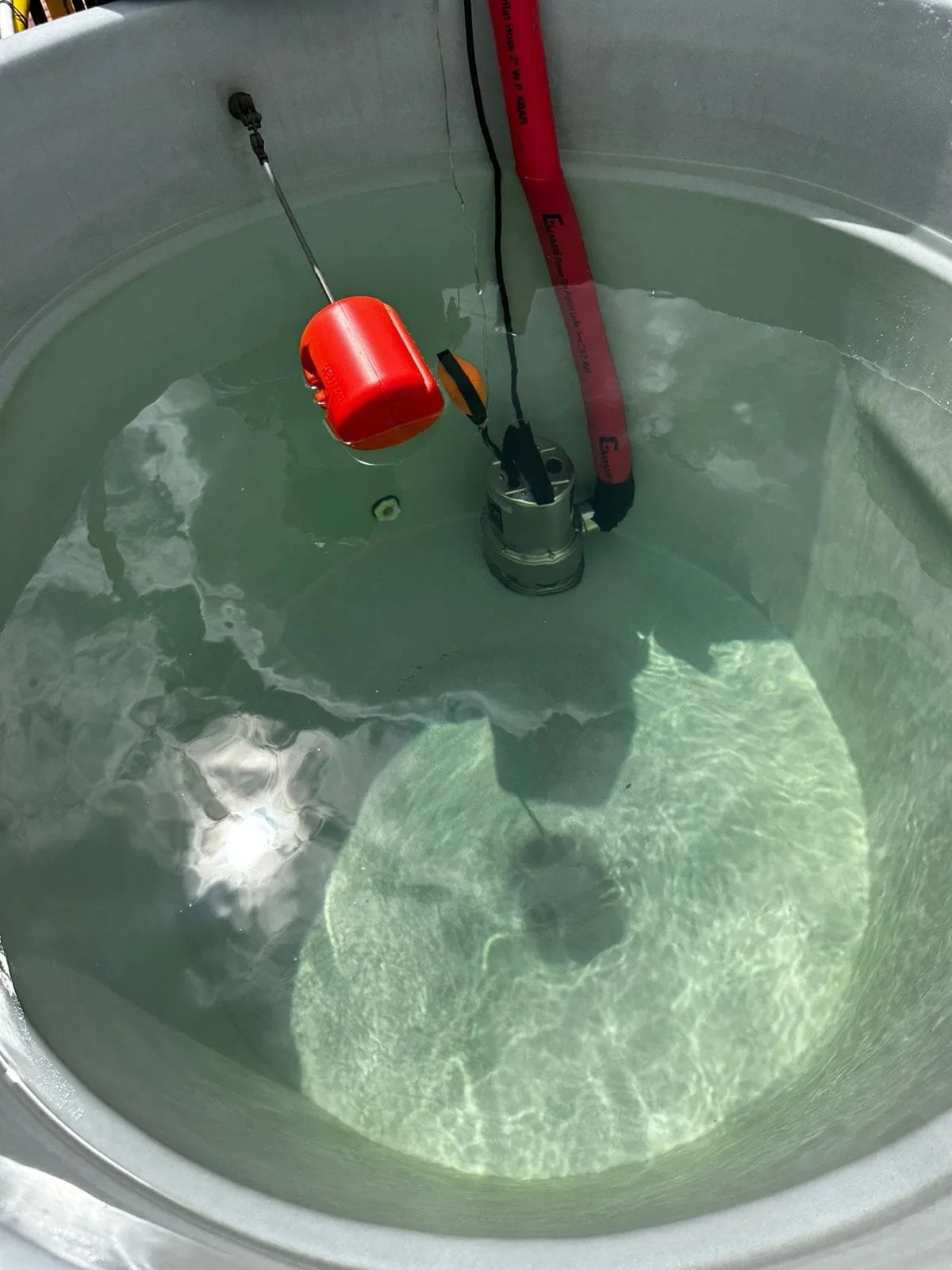 Un tanque con agua y un equipo de buceo, incluyendo un regulador y una boya de seguridad, preparado para actividades de buceo.