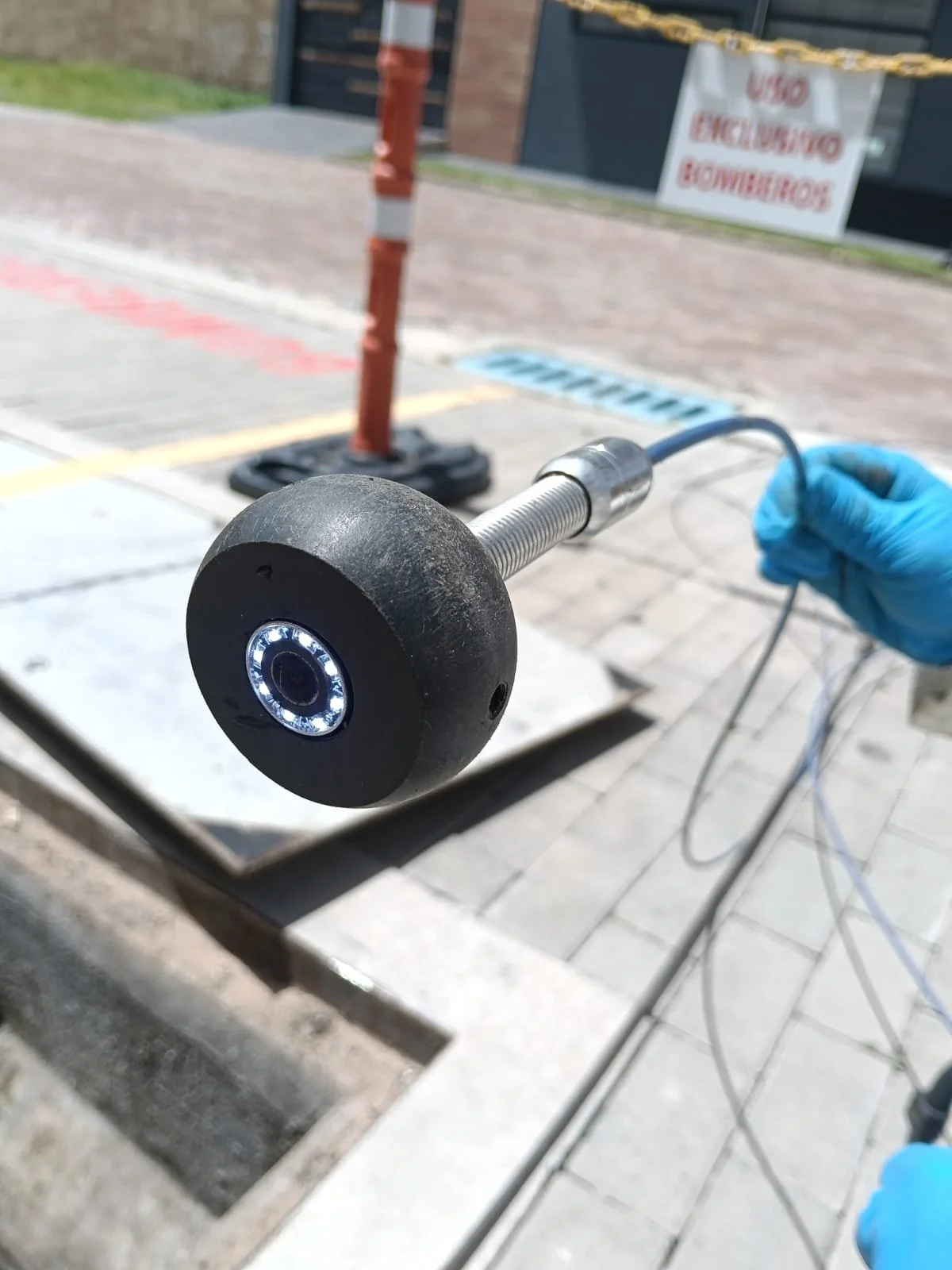Persona con guantes azules utilizando un dispositivo de inspección con camara