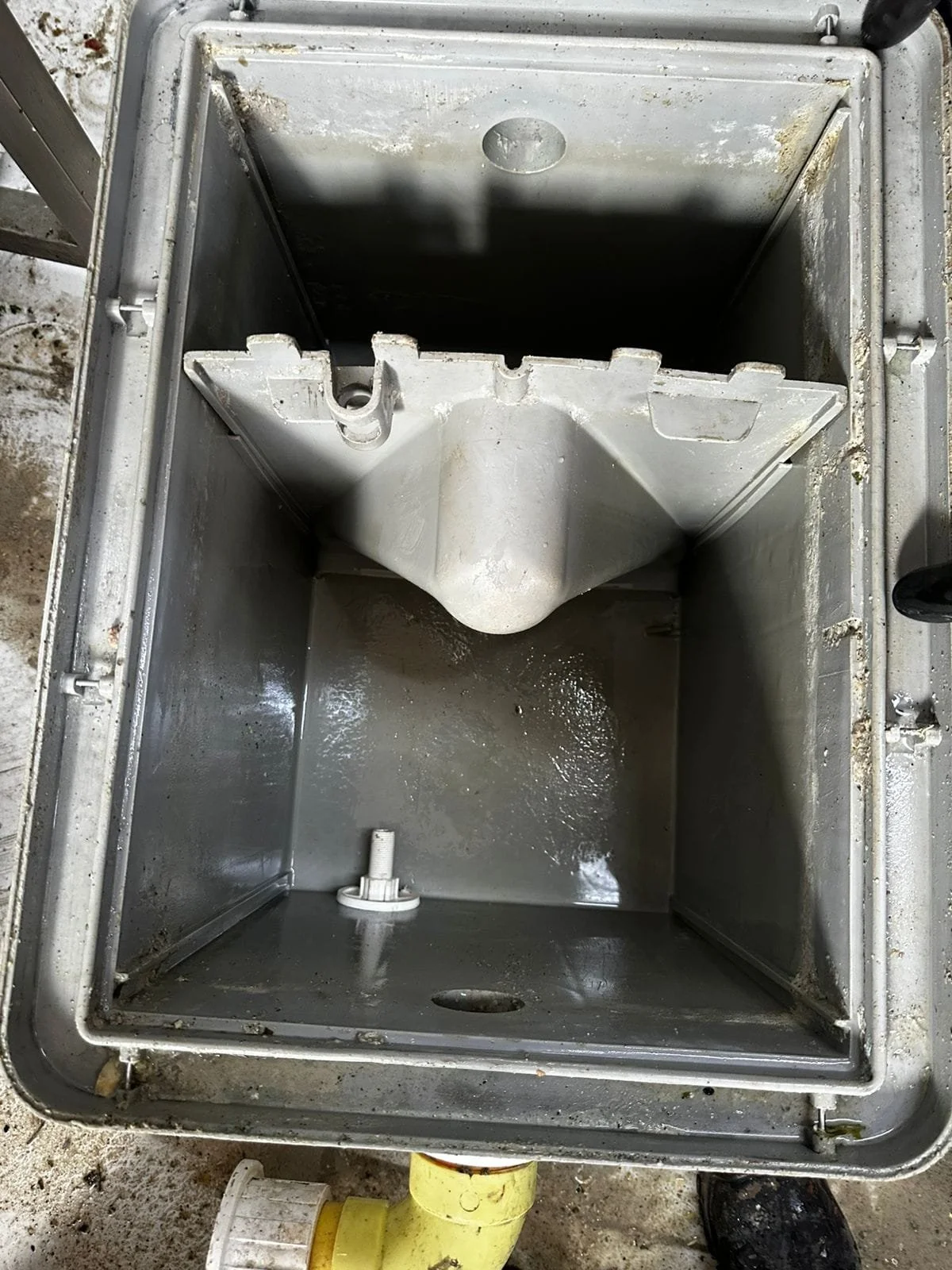 Cuadro de control eléctrico de fibrocemento abierto y vacío, con componentes internos y cables alrededor.