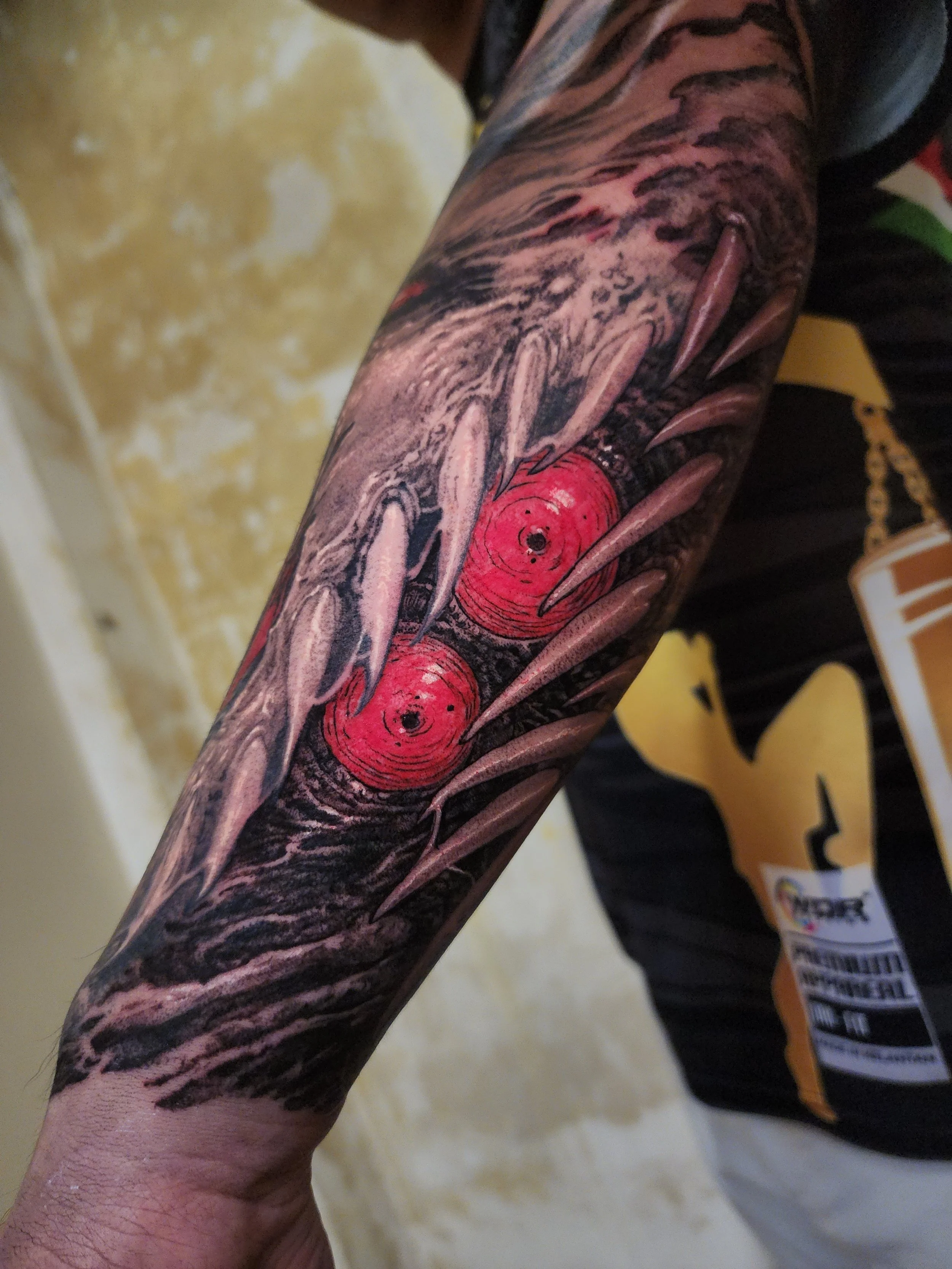 Close-up of a tattooed arm with a colorful design, including red roses and black and gray shading.