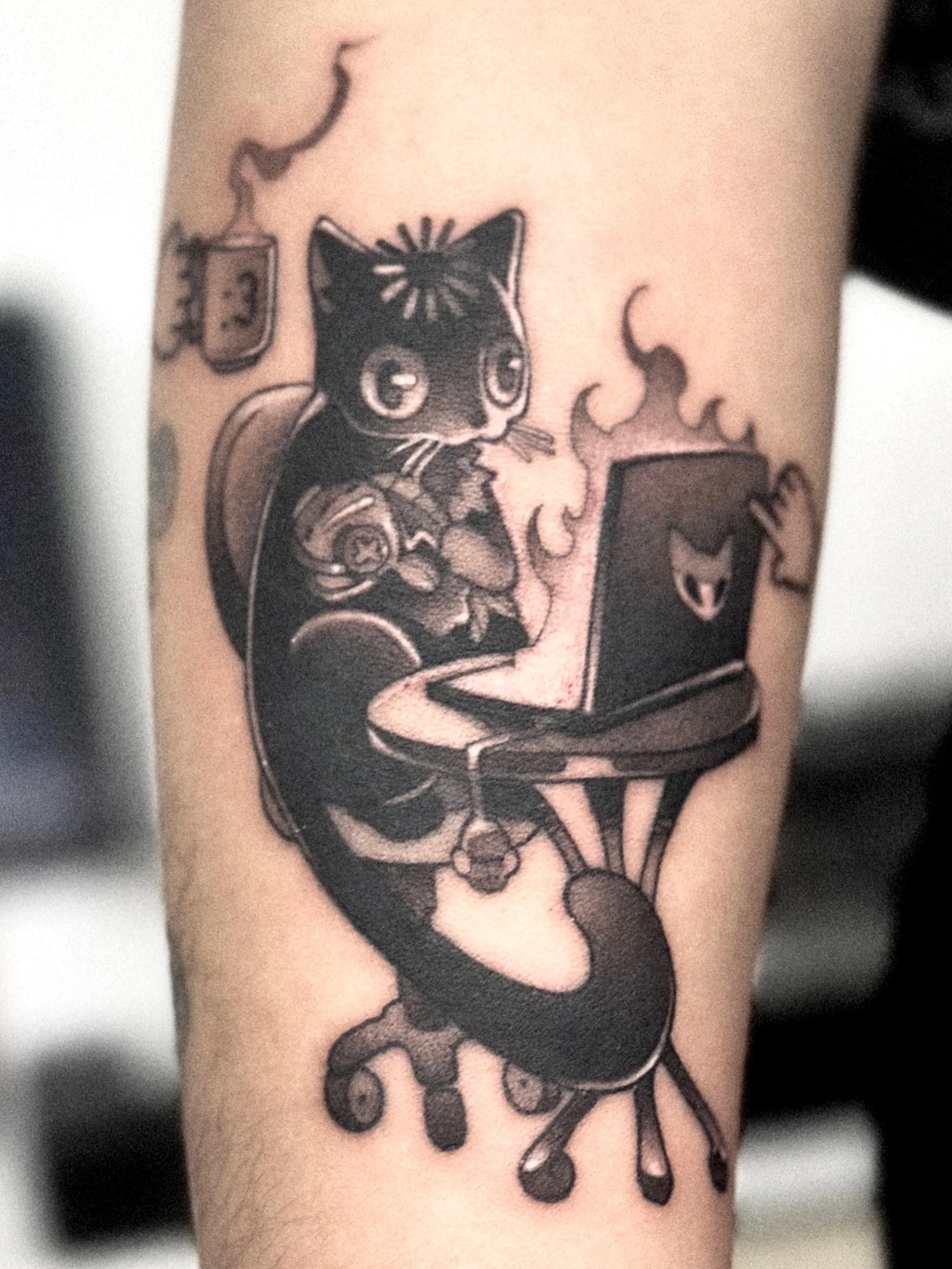 Tattoo of a black cat sitting inside a coffee cup with steam rising, on a person's arm.